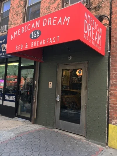 Bright red awning in front of a brick building. The awning has white letters that spell "American Dream Bed & Breakfast."
