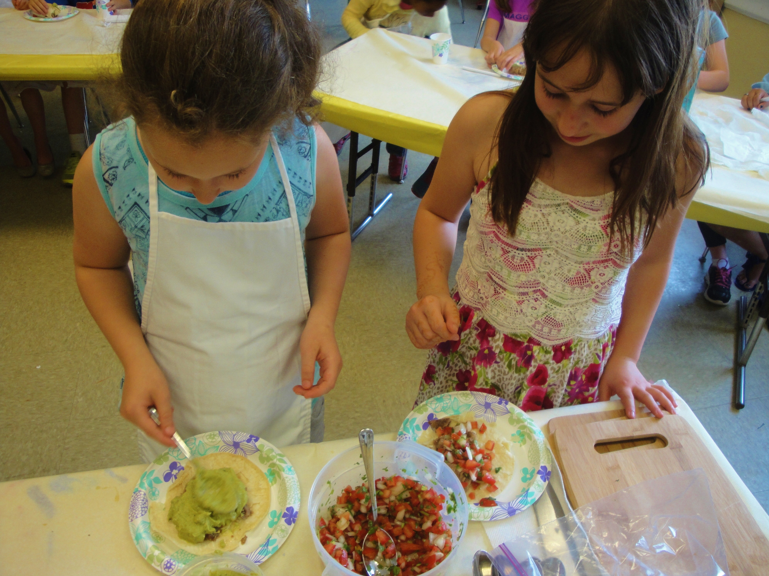 Adding guacamole and pico de gallo to carnitas tacos
