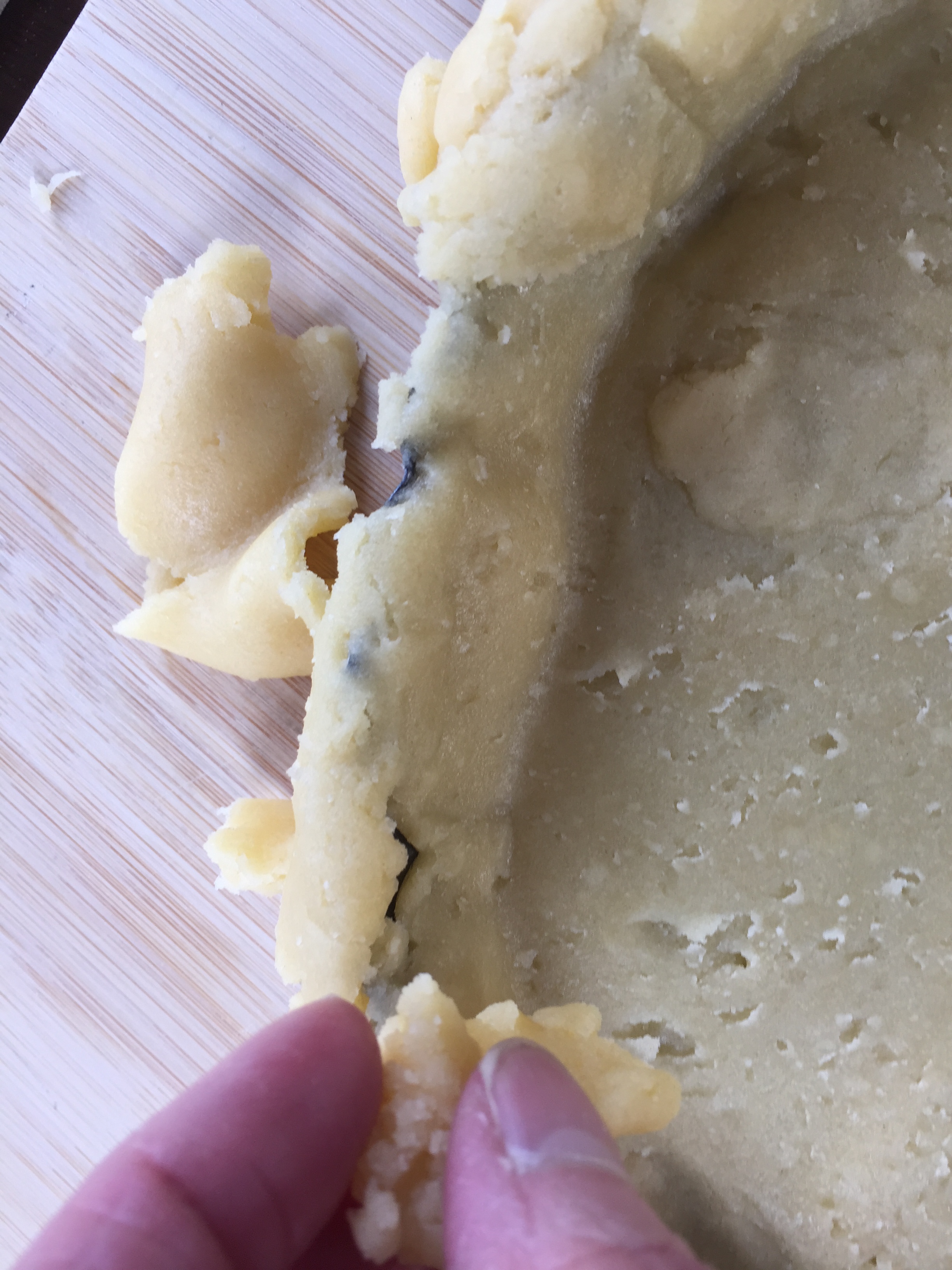 Mending torn pieces by pressing extra scraps into the pastry. 