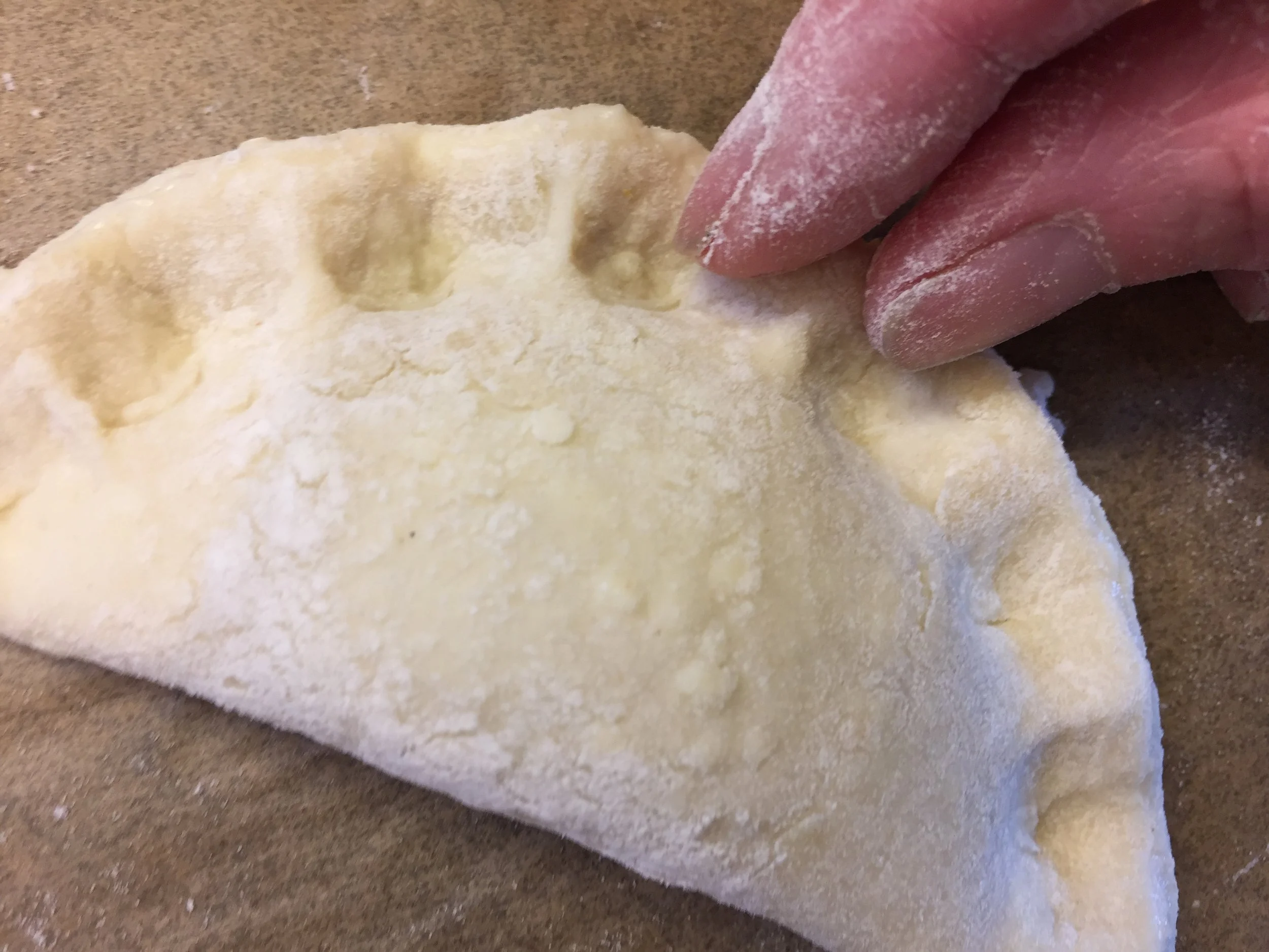 Crimping the edges with fingers.
