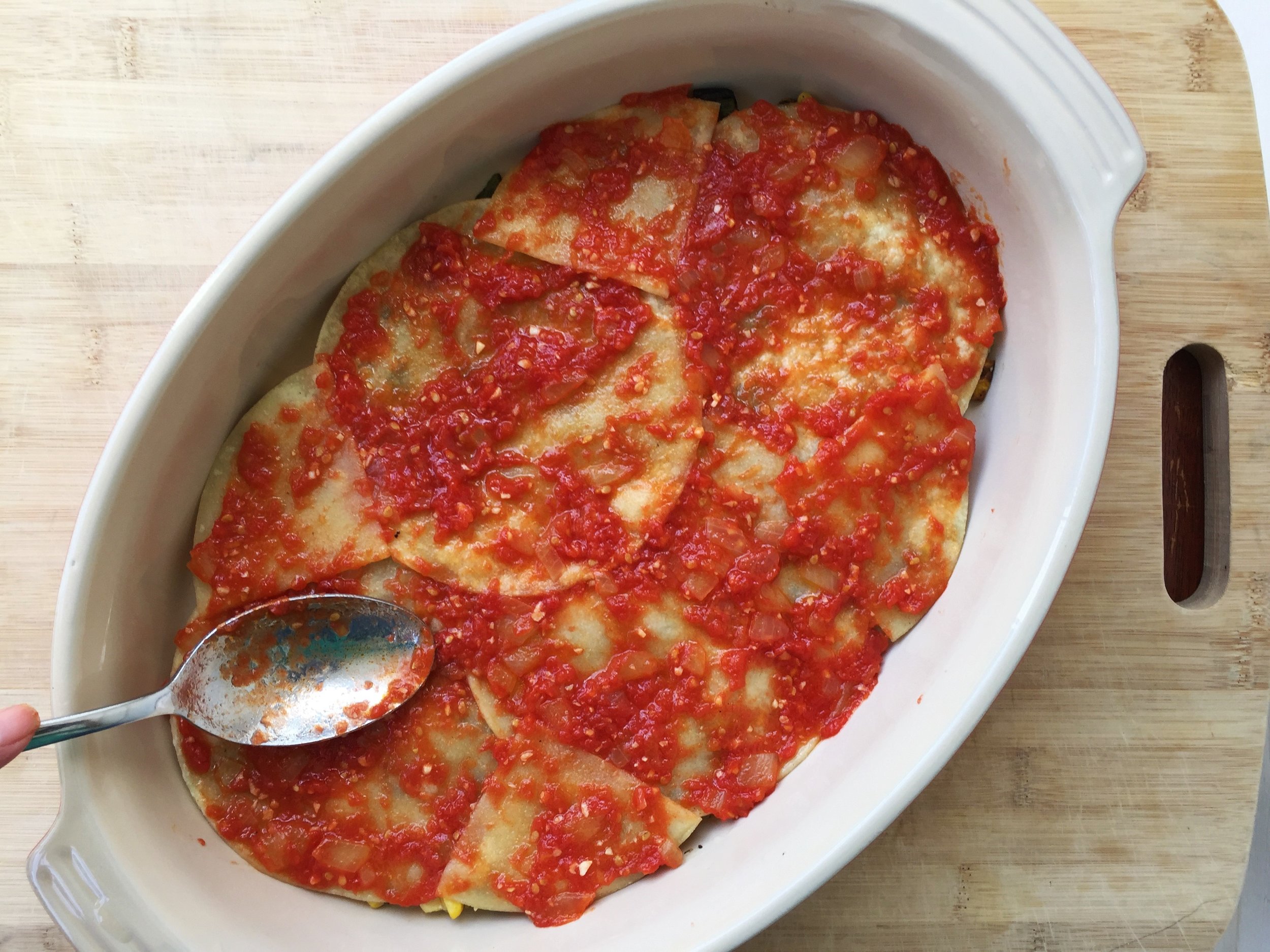 Half the tomato sauce spread over the tortillas.