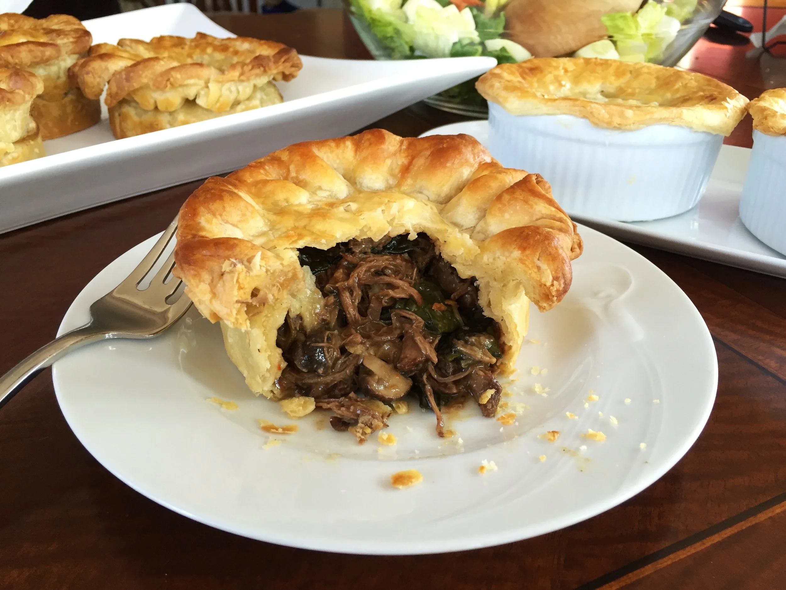 Beef and Mushroom Pot Pies. The pie that has been opened in front, and those behind to the left, were made in a springform pan and unmolded for serving. On the right are pies made in a ramekin with simple pastry tops.