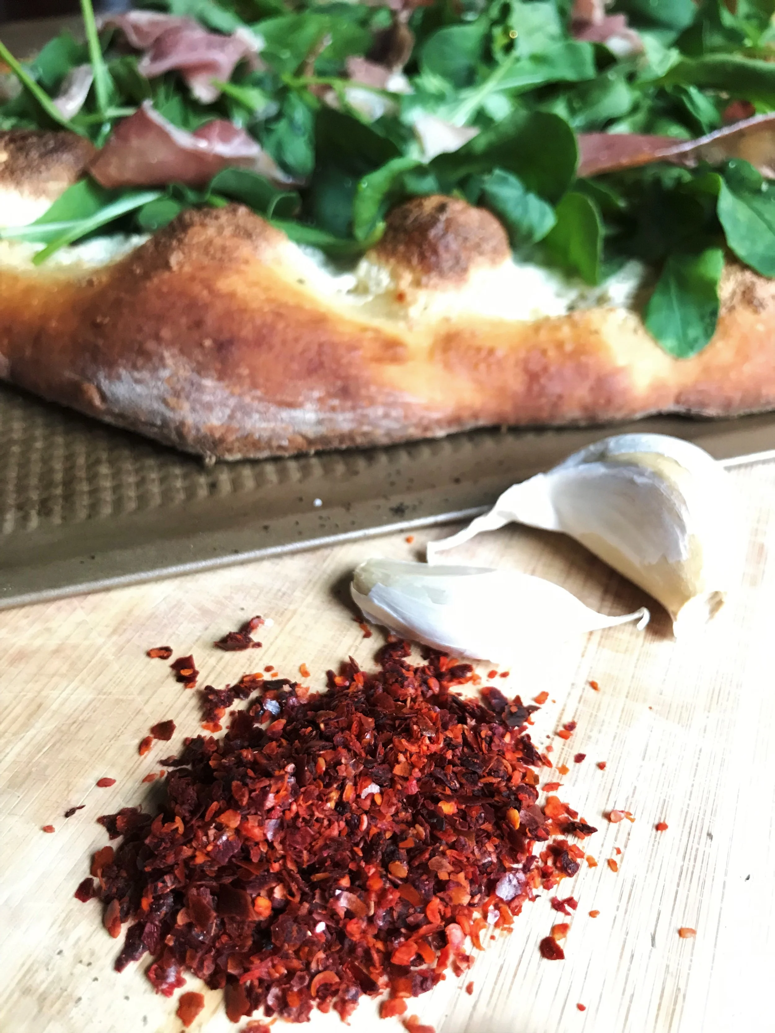 Aleppo pepper with garlic cloves and Arugula and Prosciutto Pizza.jpg