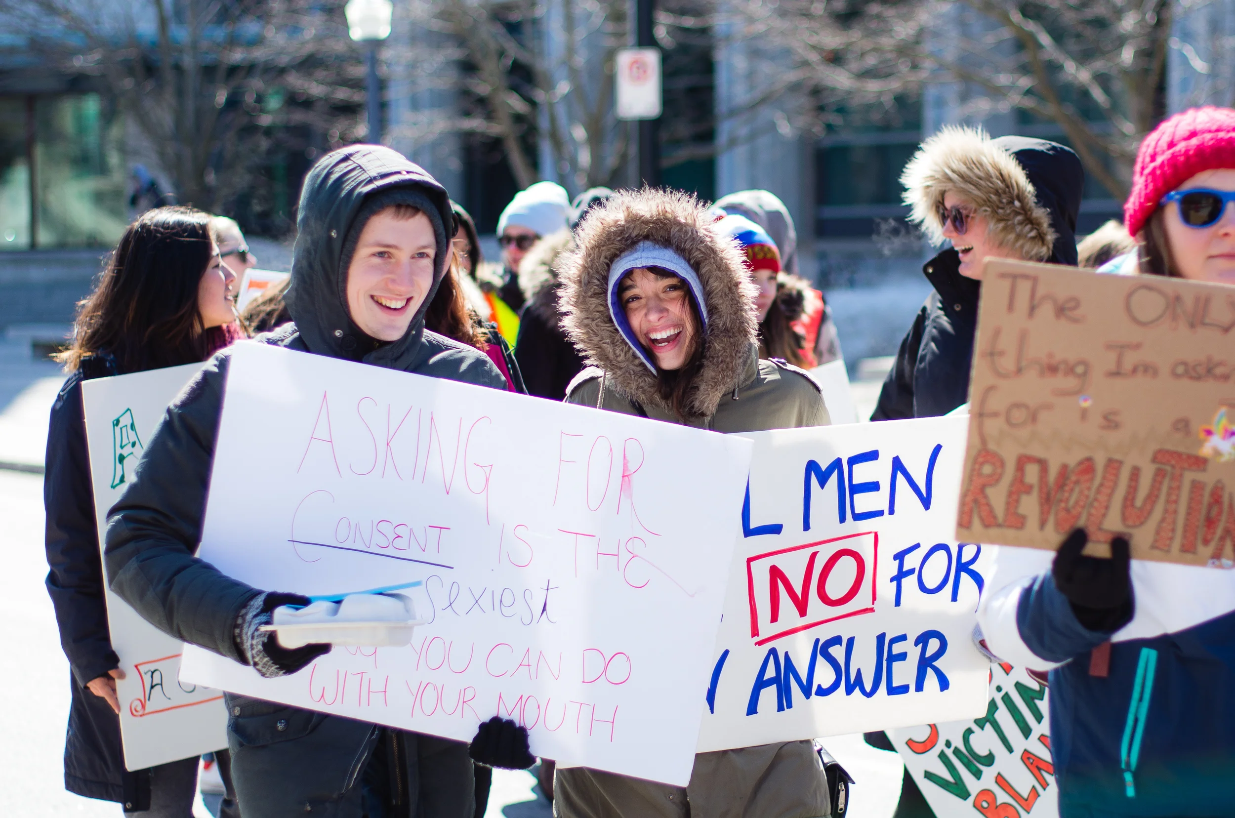 Two marchers hold signs discussing consent.