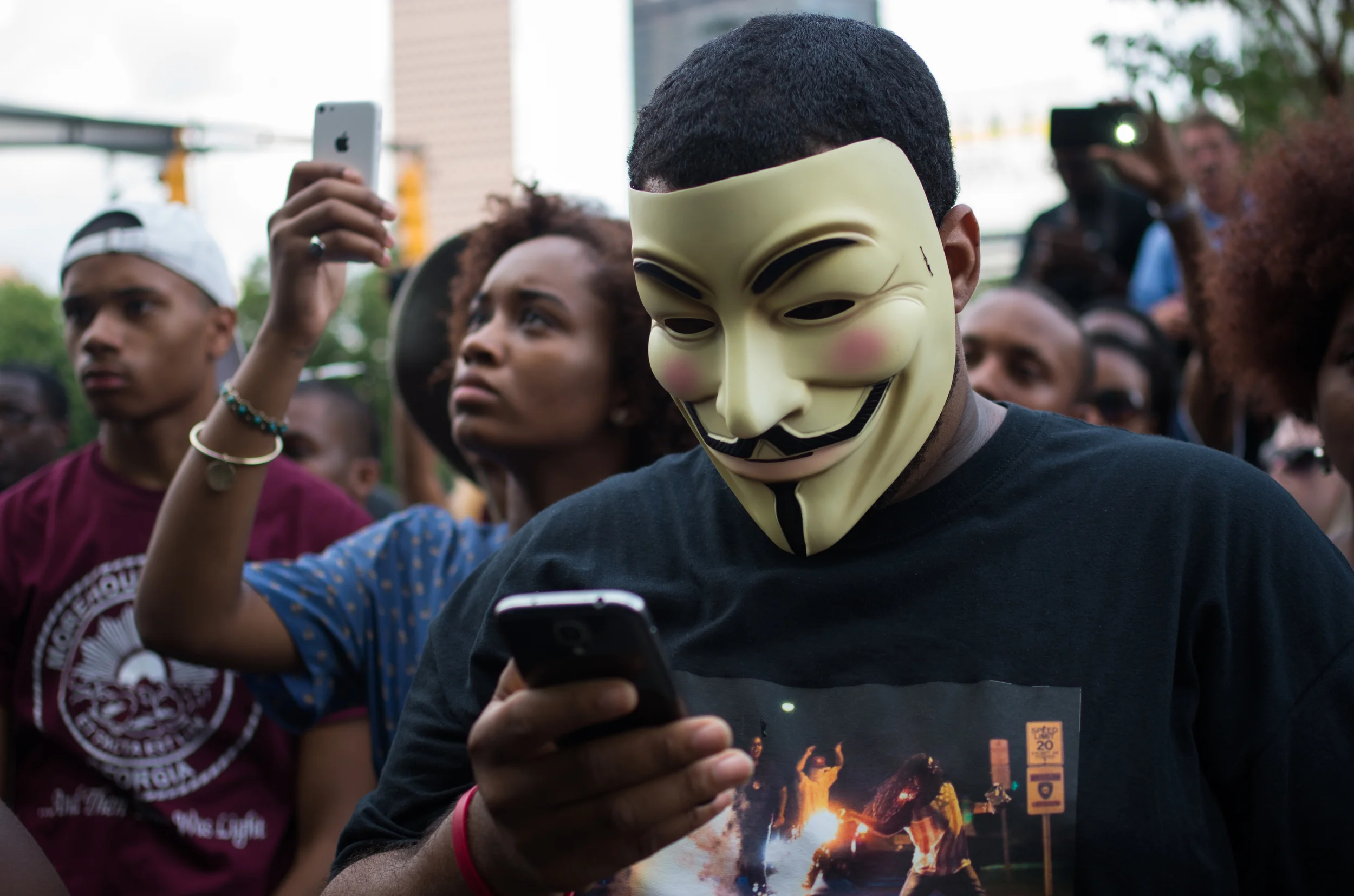 The photograph on this man's shirt is Robert Cohen's now-iconic photo of a man (@eyefloodpanties on Twitter) throwing a tear gas canister away from children in Ferguson, MO.
