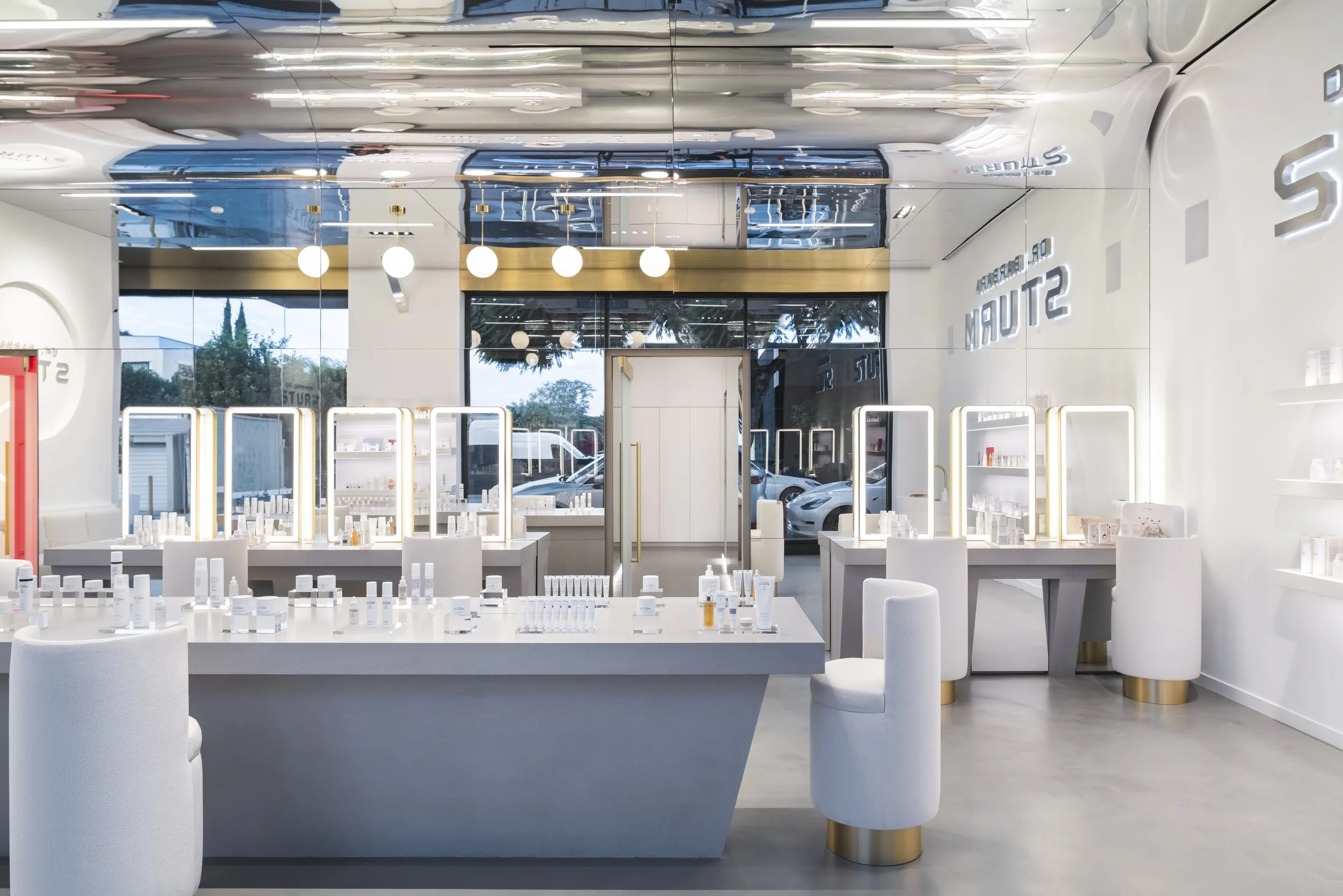 Modern skincare store interior with white decor, mirrored ceiling, and display tables filled with skincare products.