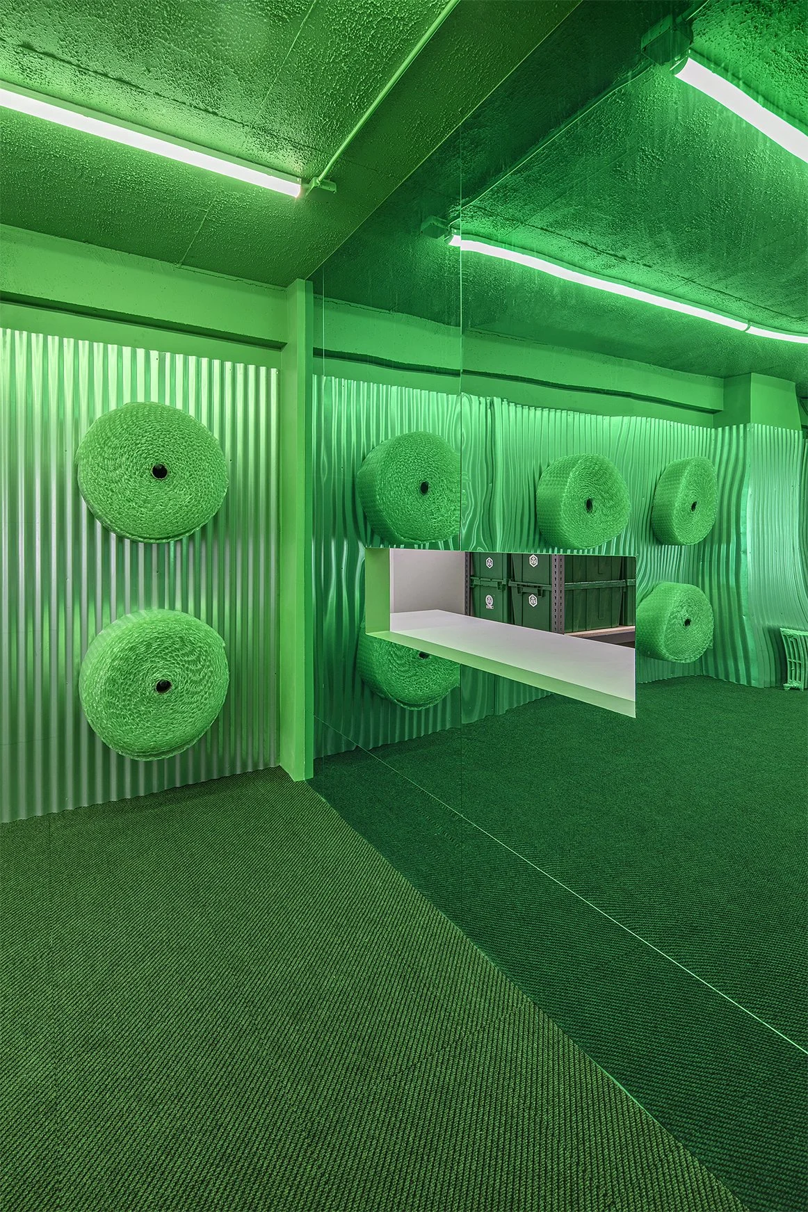 Green room with rolls of material on walls and mirrored surfaces