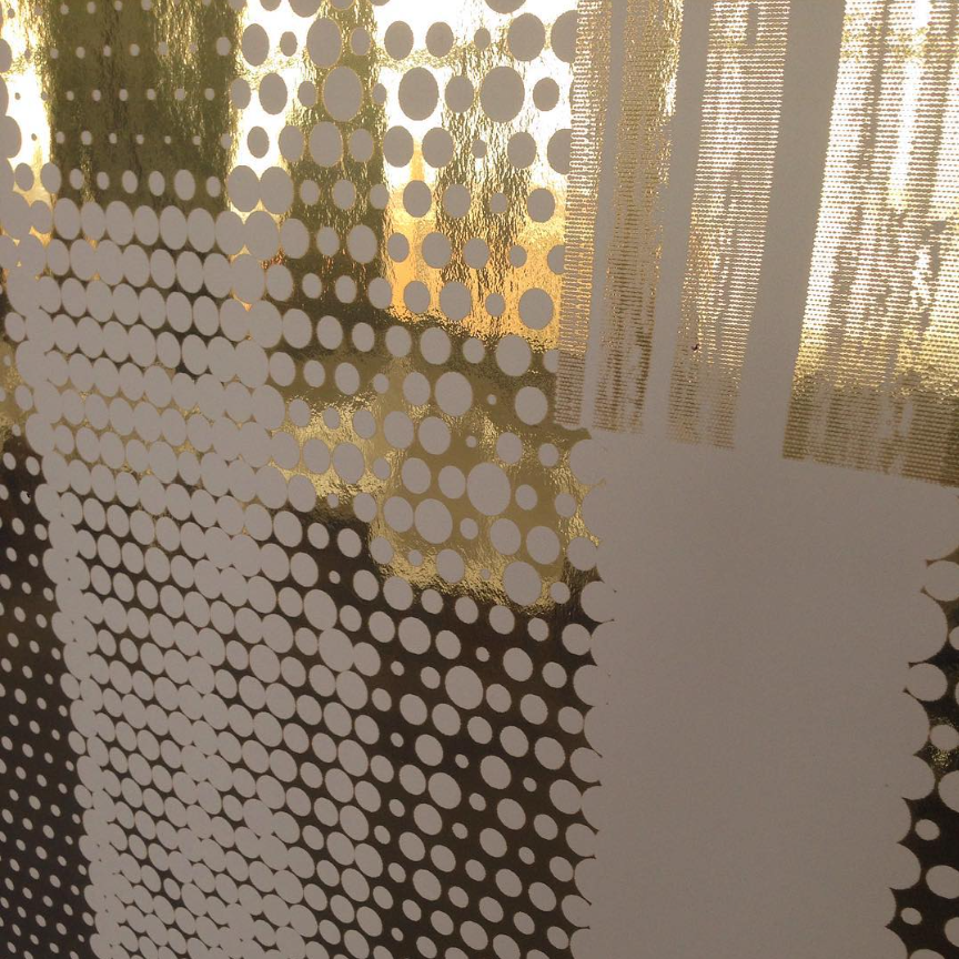 Abstract design with metallic gold and white dotted pattern on a reflective surface.