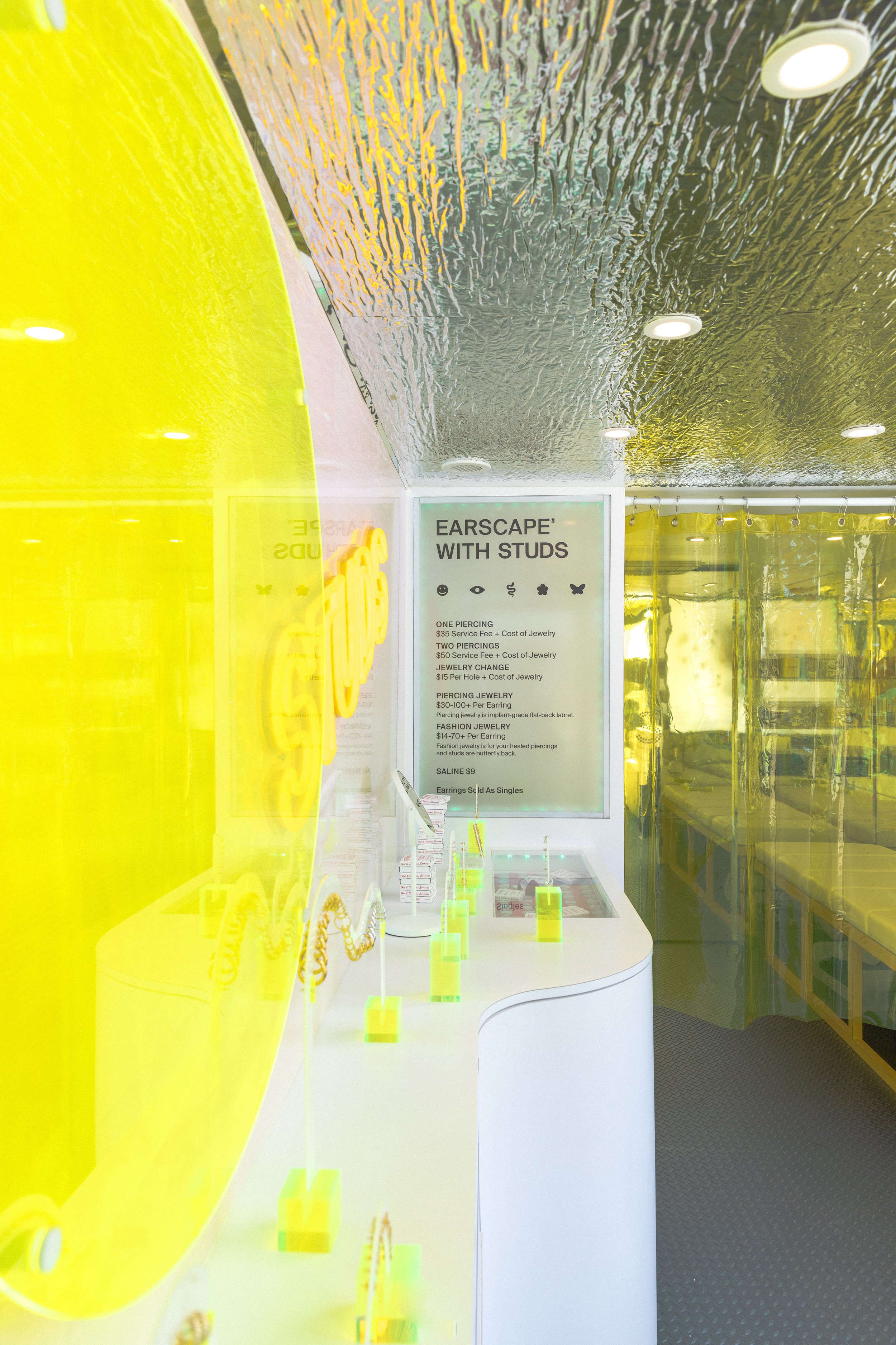 Interior of a modern studio showcasing ear piercing services and jewelry display with bright yellow decor.