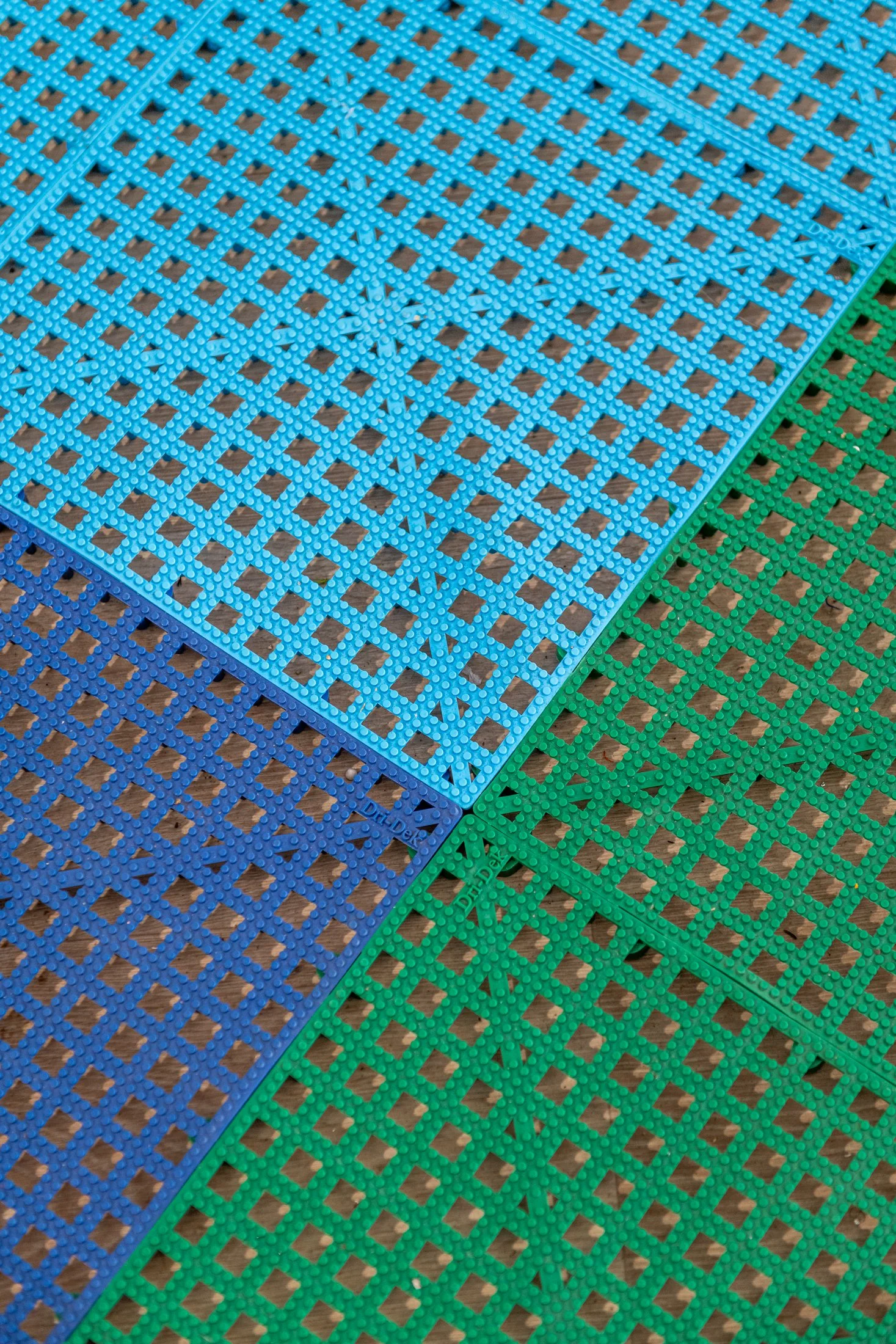 Close-up of interlocking blue and green textured floor mats with lattice design.
