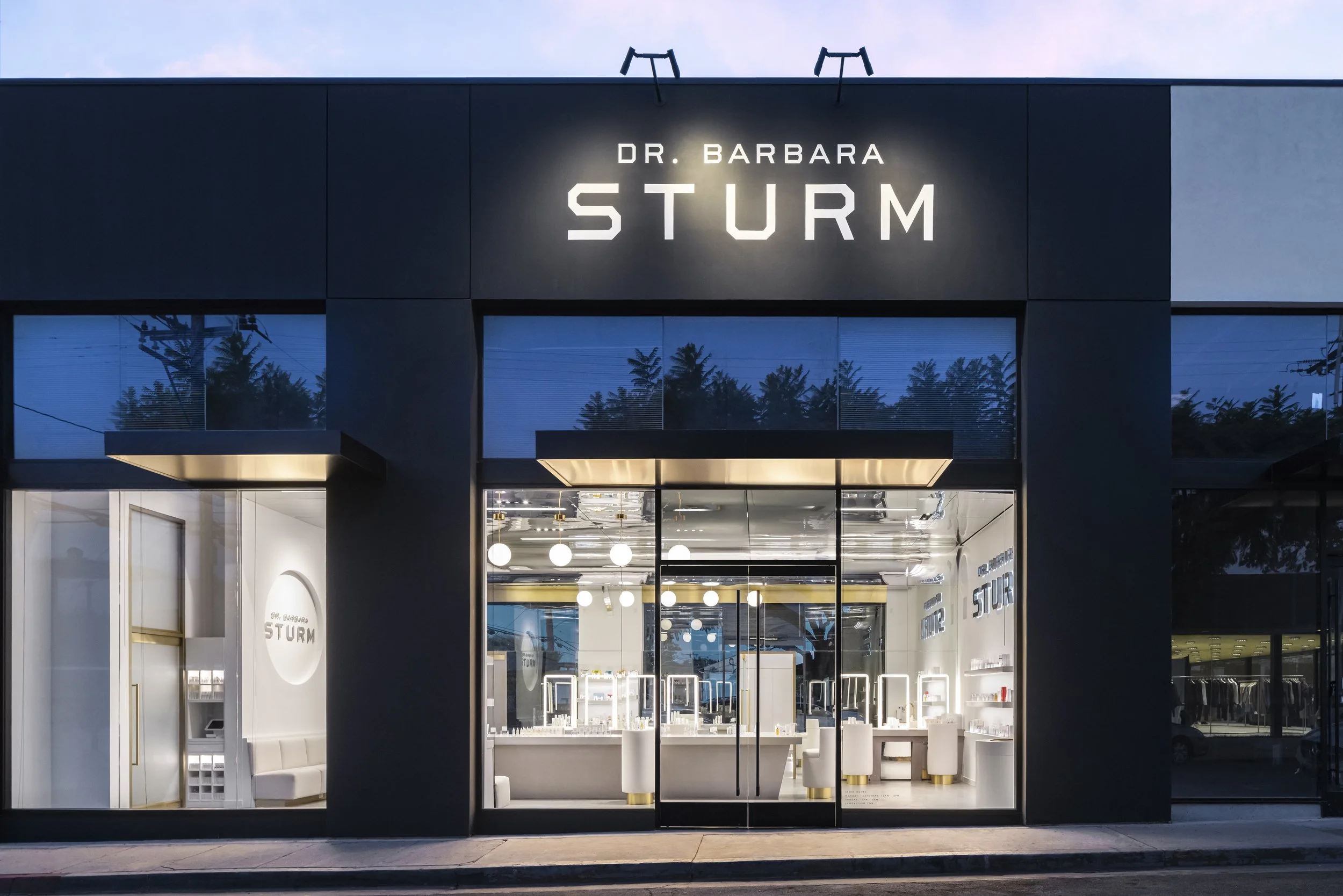 Front view of the Dr. Barbara Sturm store with illuminated signage, large windows, and modern interior design.