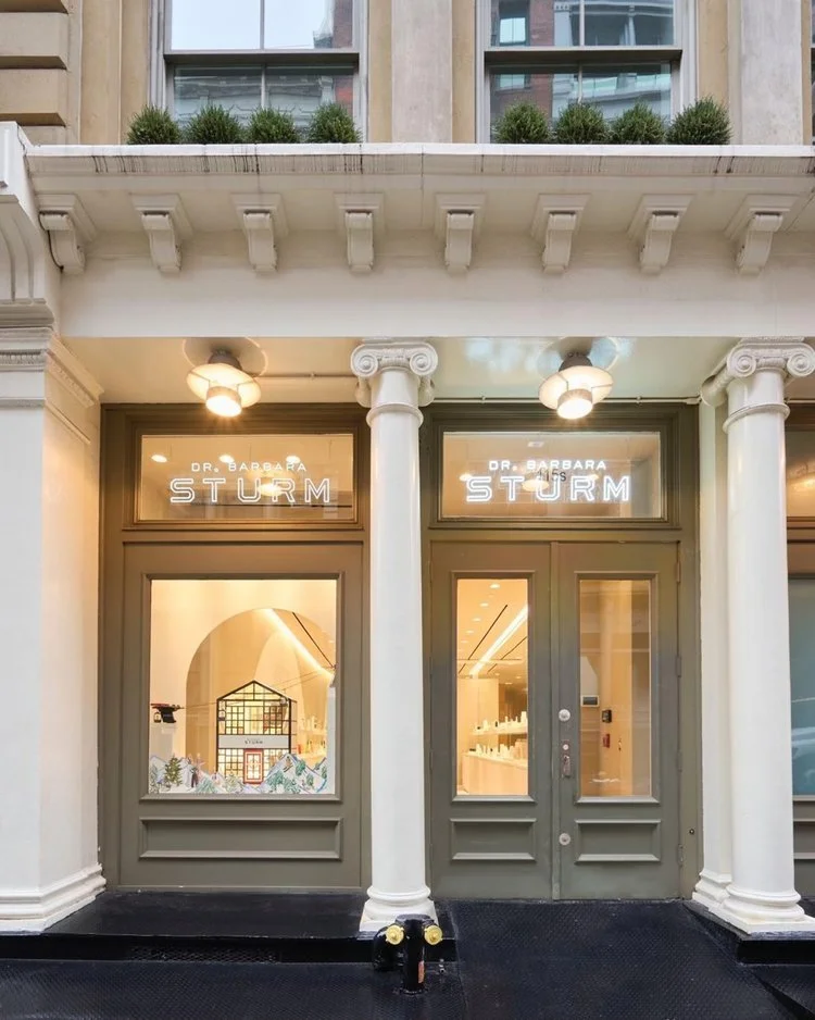 Exterior of a storefront with "Dr. Barbara Sturm" signage, featuring large windows and two entrance doors flanked by white columns.