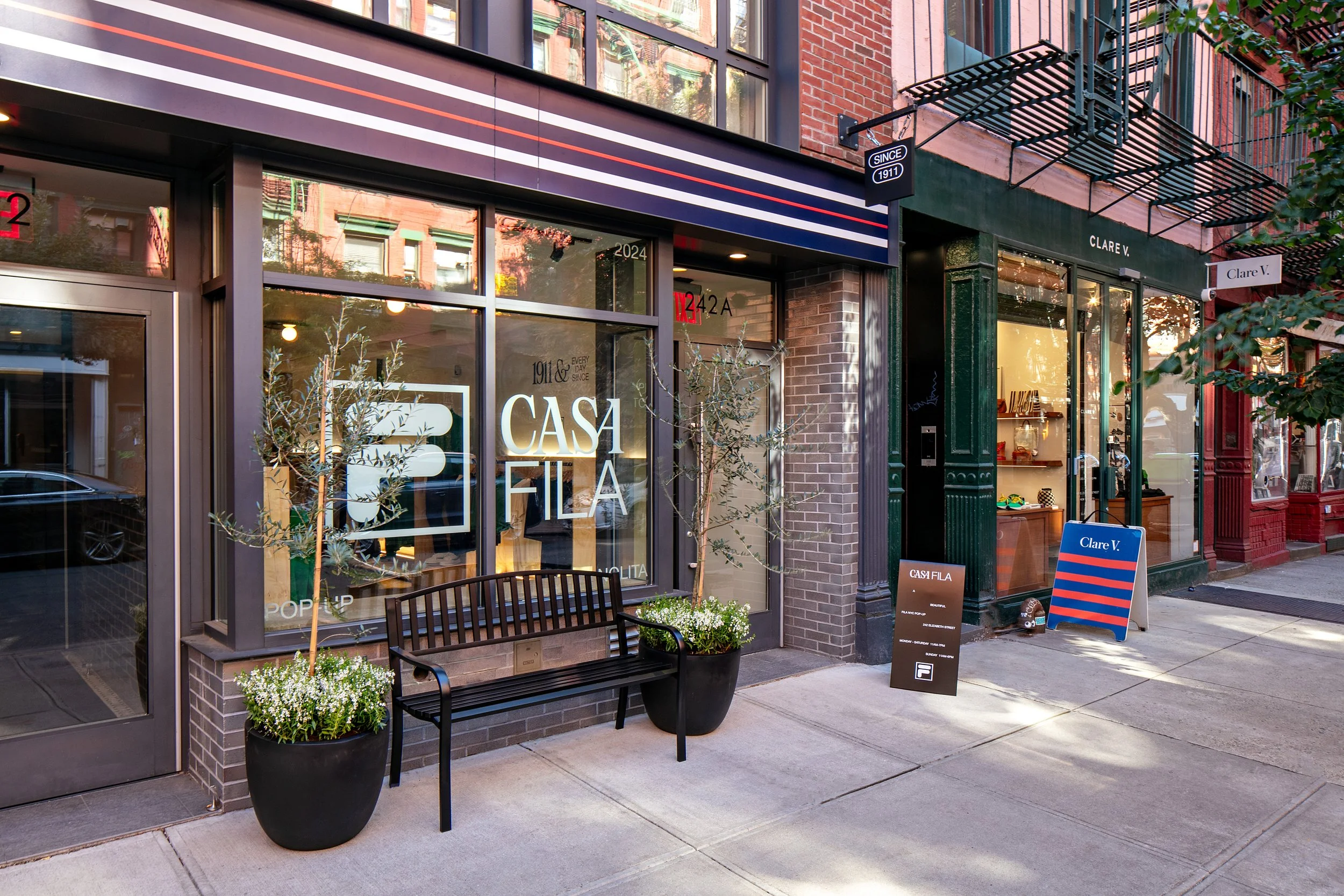 Street view of two storefronts: Casa Fila with a bench and potted plants in front, and Clare V. with window displays, located on a city sidewalk.