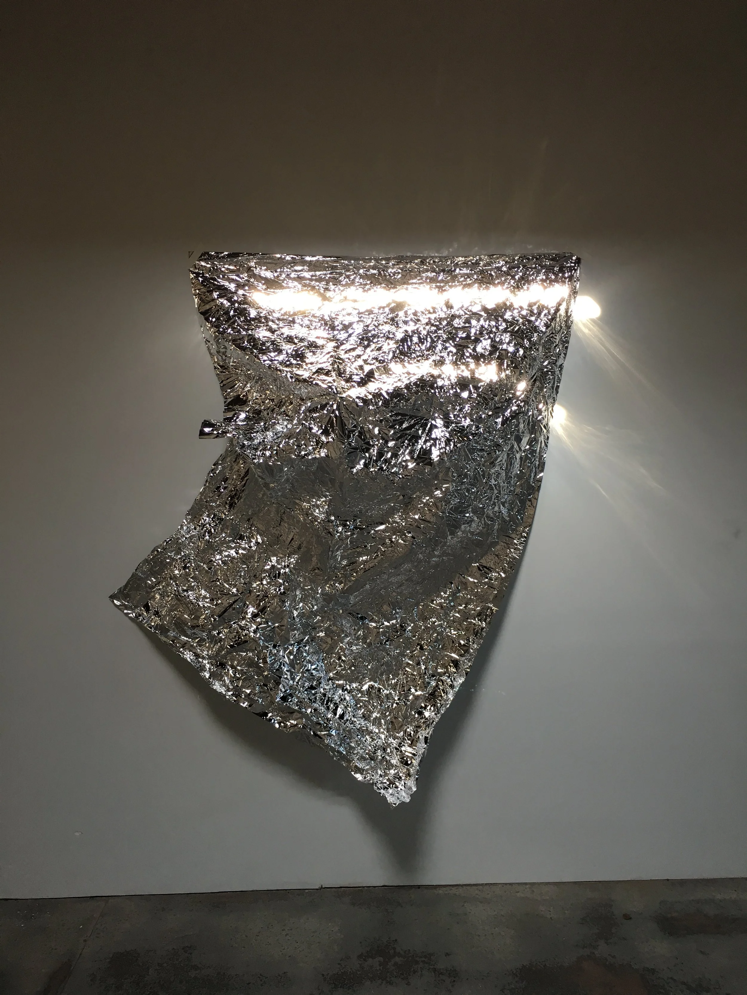 Crumpled foil illuminated on a wall