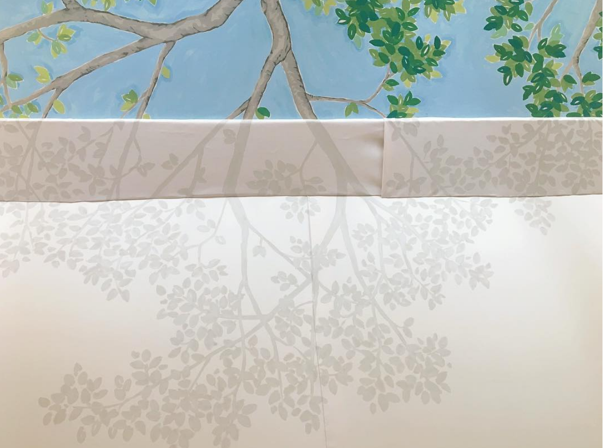 At the intersection of where the tree grows beyond the tent and the branches continue, Art & Atmosphere completed the trompe-l’oeil effect by painting the shadow of the leaves and branches onto the canvas duck. This supports the illusion that the tree is much larger than the room.