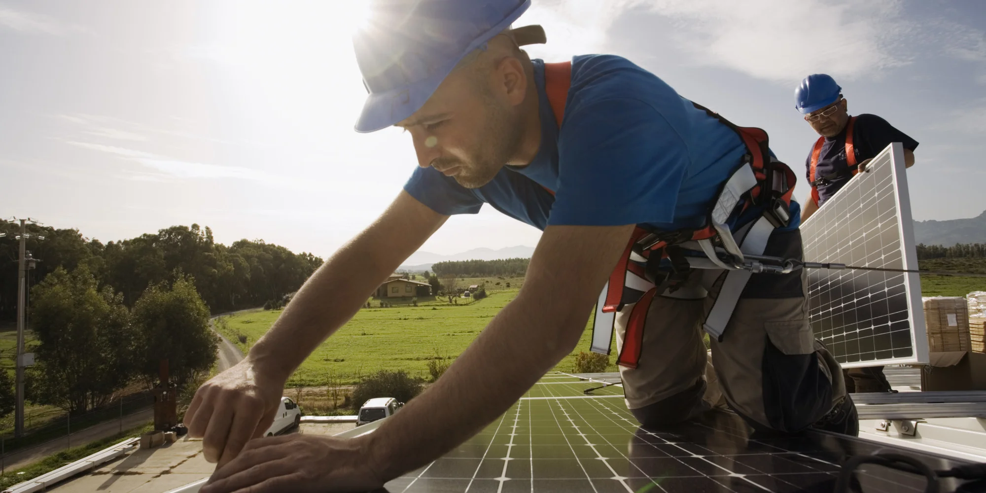 Technician installing off-grid solar system with inverter, panels, and battery bank.
