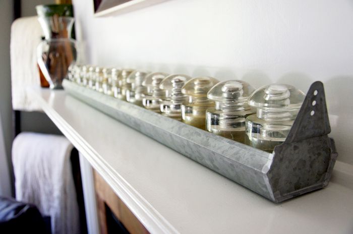 Yes, you can have insulators setting around as decor, but you can also pair them up with other vintage items to create unique and beautiful piece. For instance over at Natalme , I found this pairing of glass insulators with a vintage chicken feeder. It makes a wonderful mantel display.