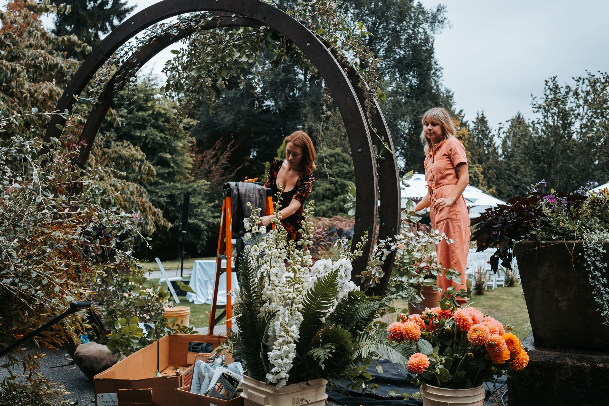 Floralista sets up the flowers and greenery to decorate the wooden circular arch outside at the Stanley Park Pavilion | Keepsake Events
