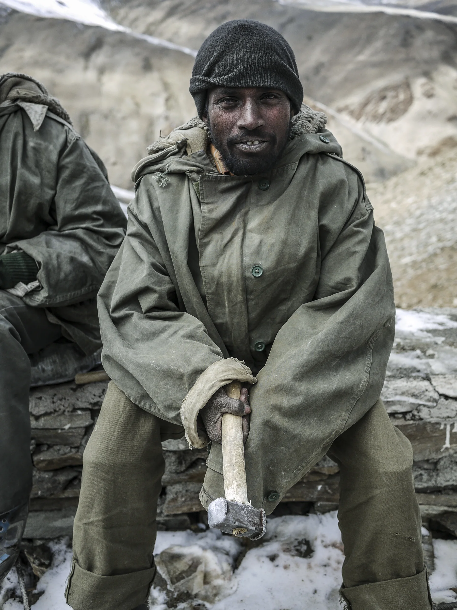 A young migrant worker wears an over-sized coat and no safety gear.
