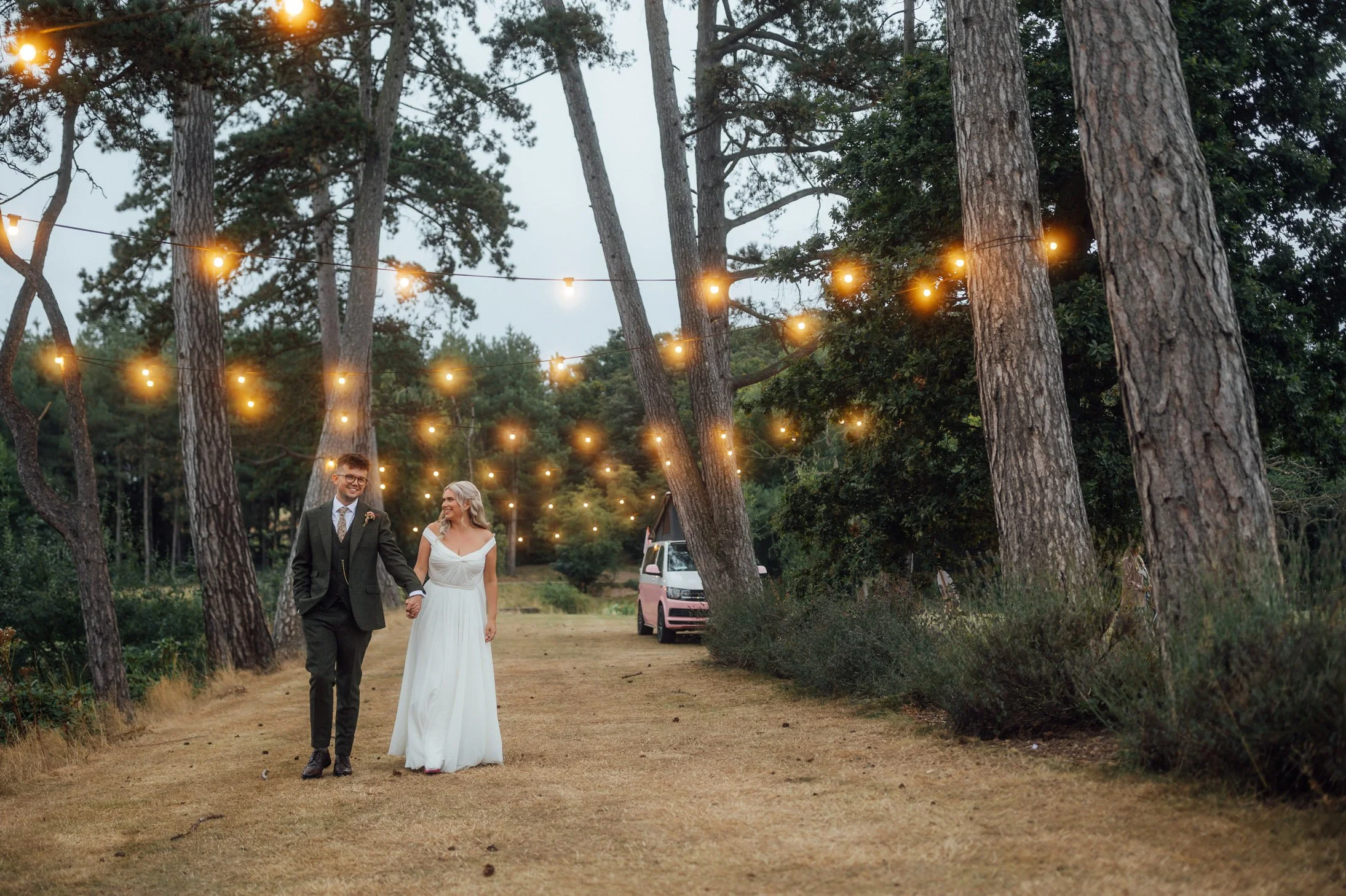 A bride and groom kissing on their wedding day outdoors with a scenic ocean view and classical pavilion in the background.