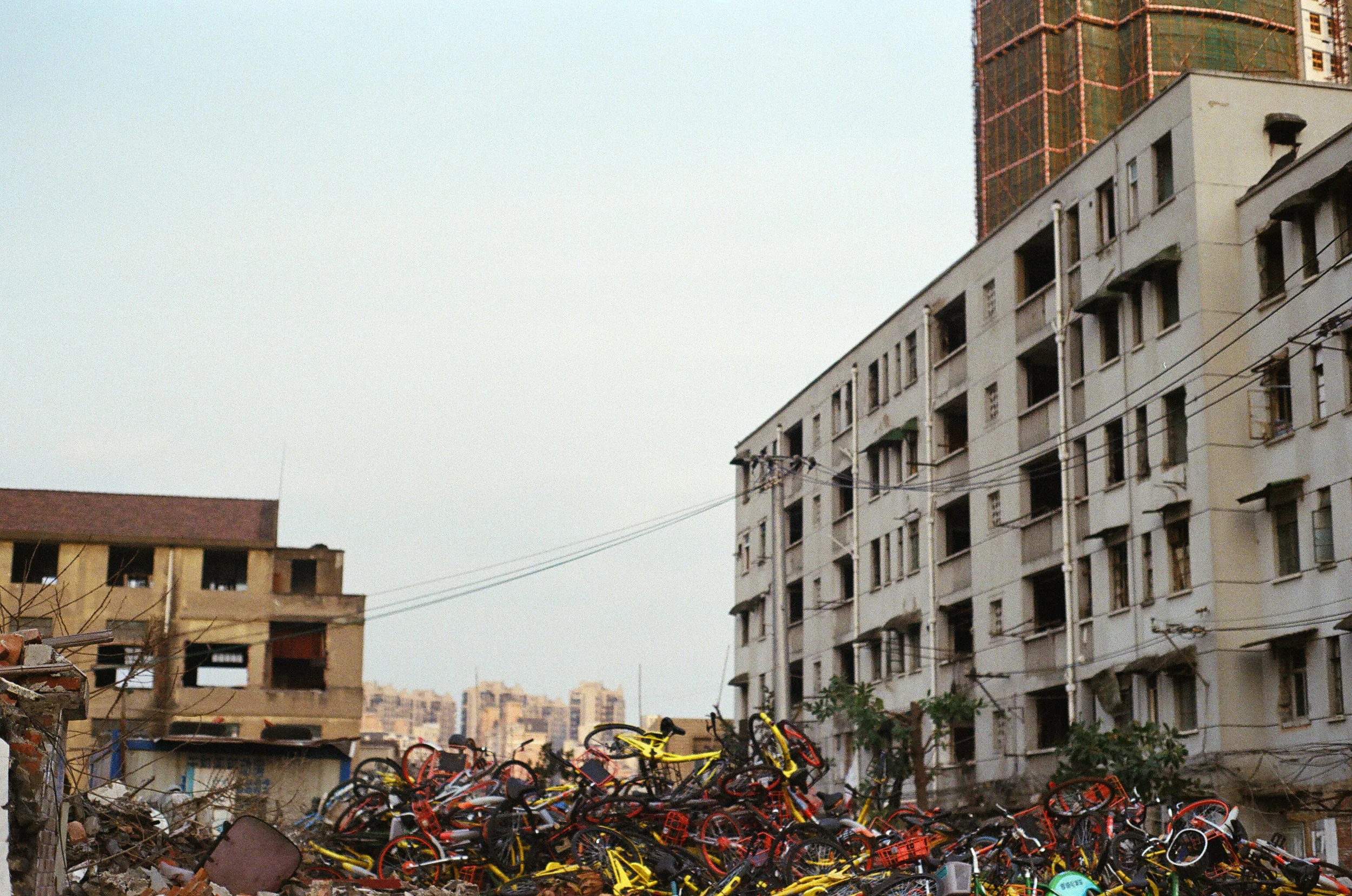 yangpu district, shanghai, 2018. these new bikes are supposed to lay across the city but now they're piled up here, next to the buildings ready to be torn down. 