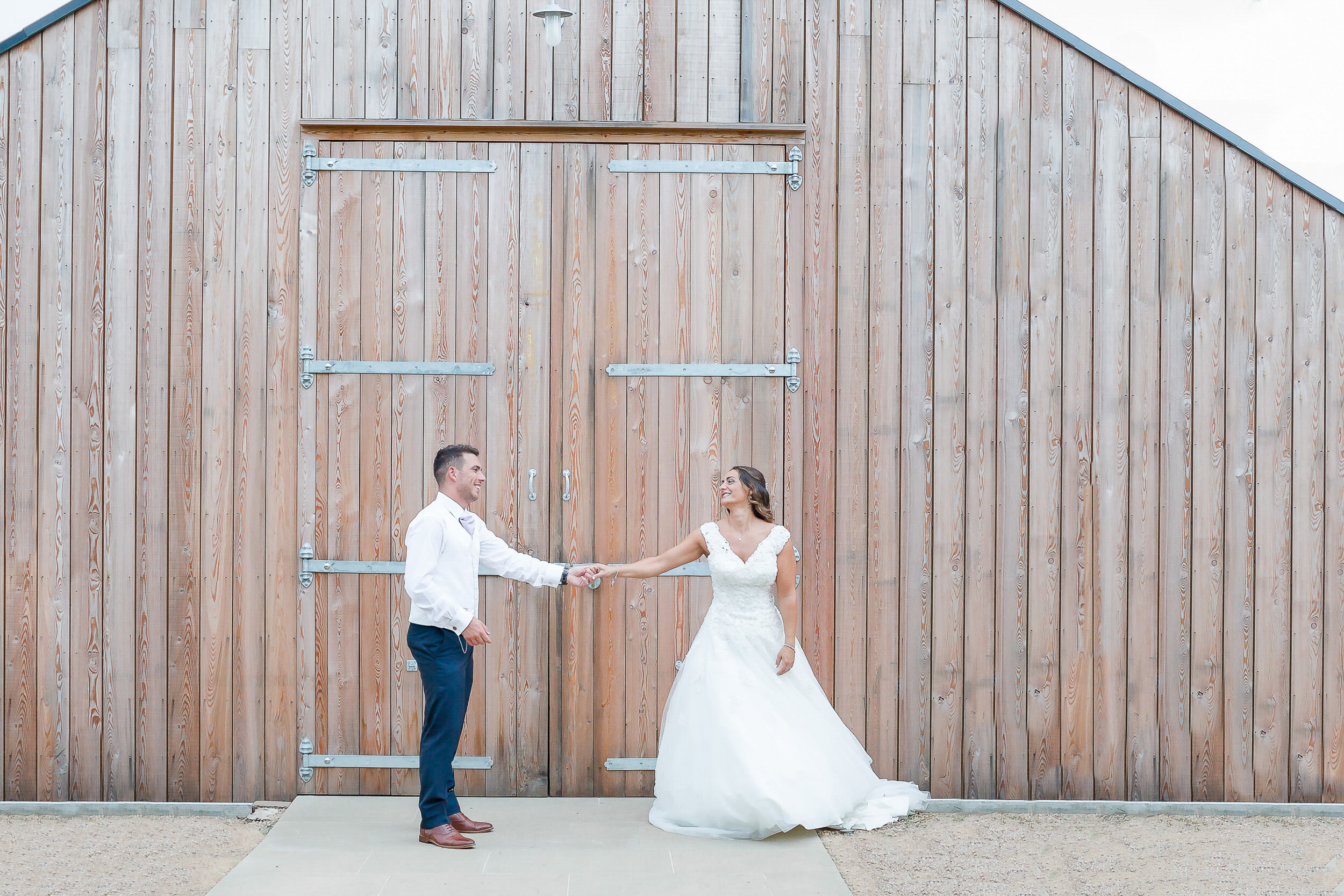 bride-groom-dancing-outside-barn-hyde-house-cotswolds.jpg