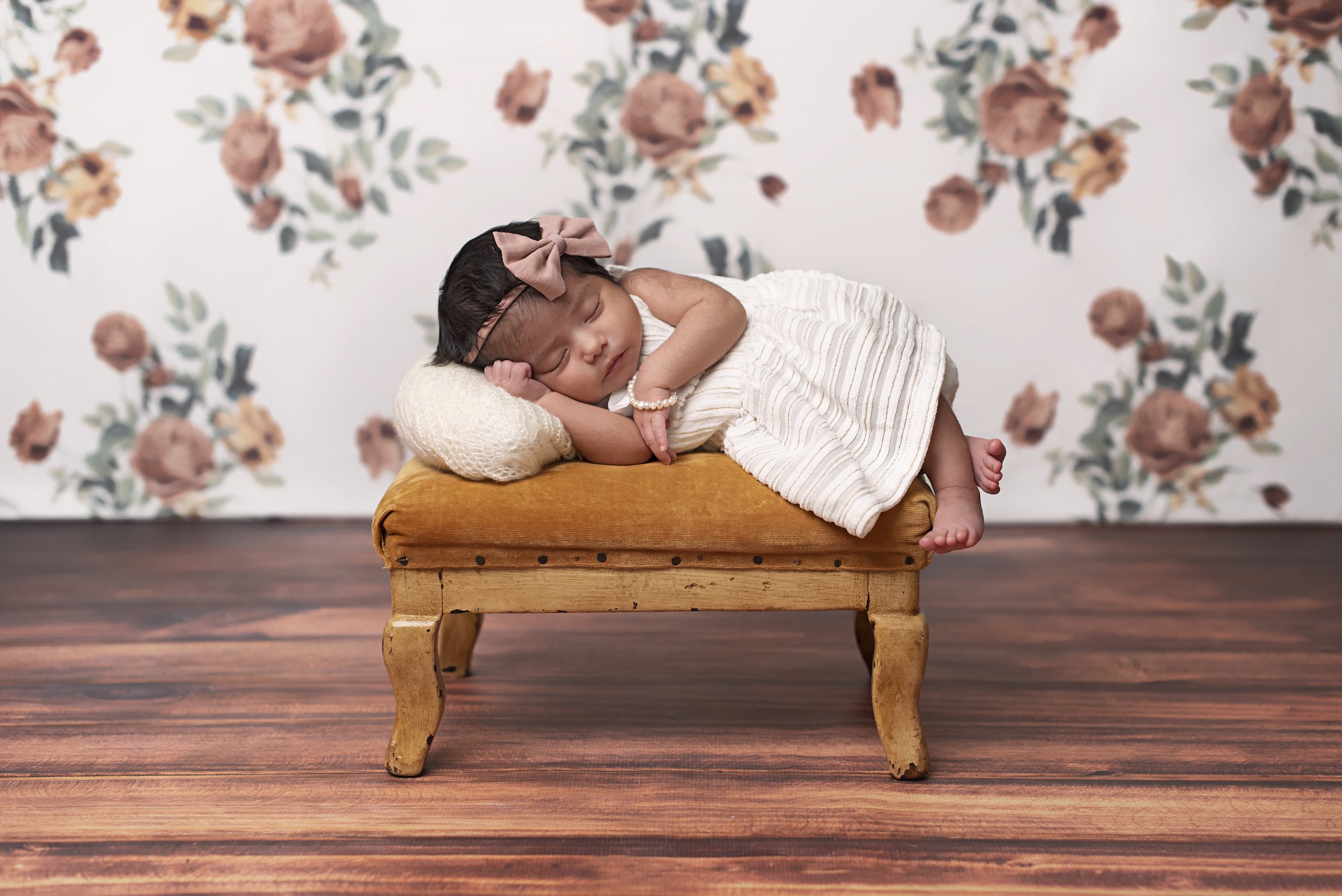 newborn girl in gown on gold velvet stool