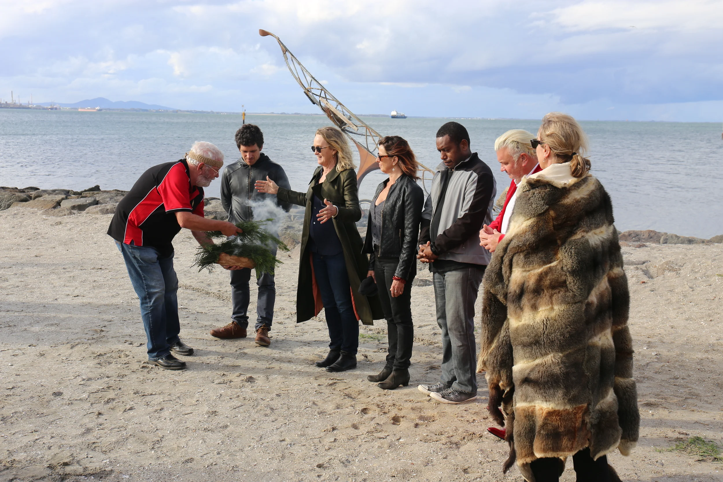 Wadawurrung Elder Uncle Bryon Powell smoking 2014 Canoe artist Benjamin Gilbert, Mountain to Mouth Artistic Director Meme McDonald, Mahony Maia Kiely, Leonard Tebegetu, Mayor Darryn Lyons and Manager of Arts and Culture Kaz Paton at the  Eastern Beach ceremony.