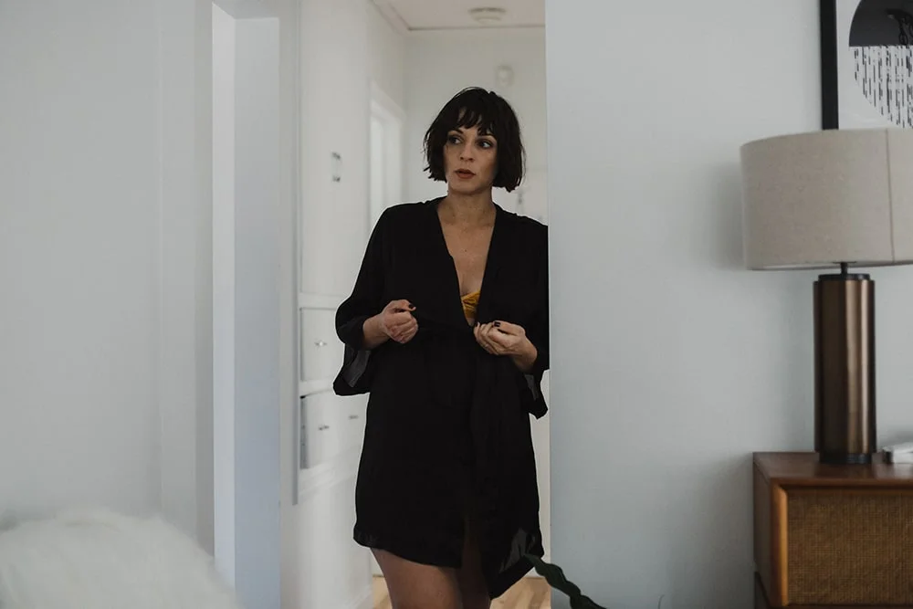 woman tying black robe in hallway