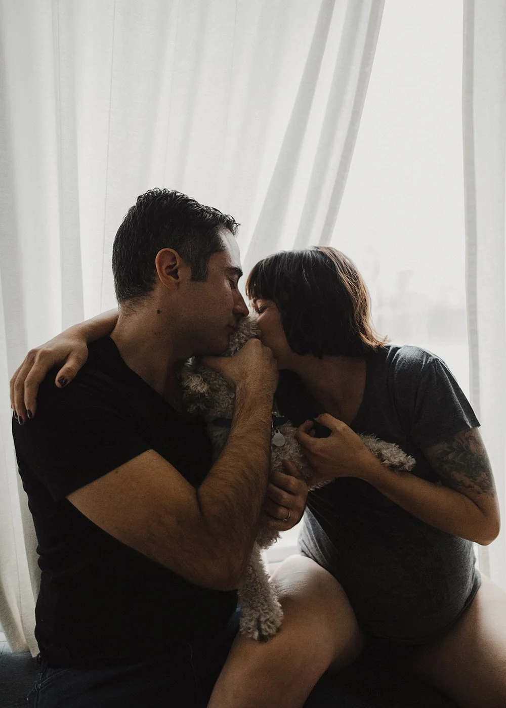 couple kissing dog and cuddling