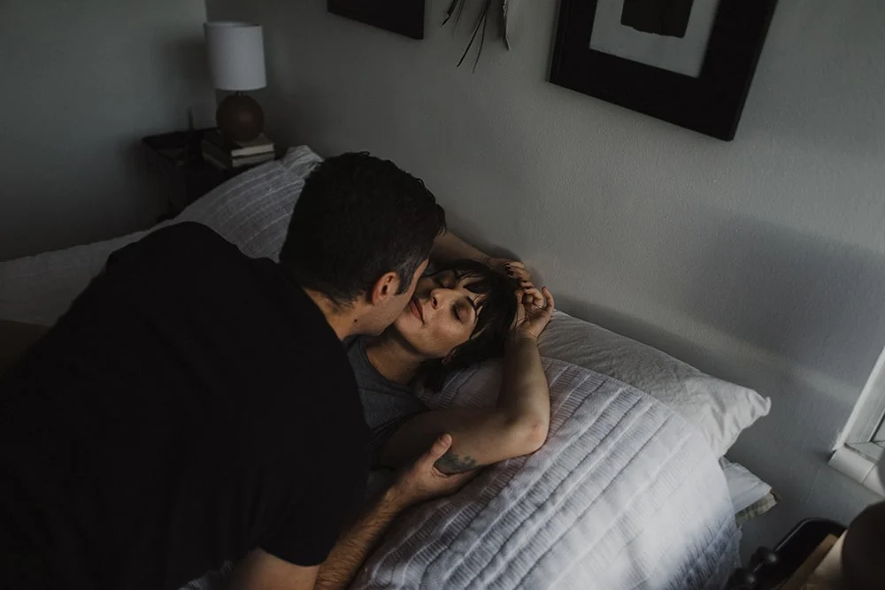 man kissing woman on lips in bed