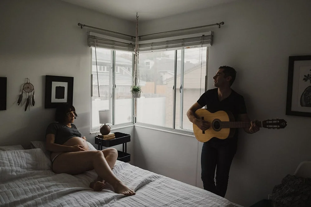 man playing guitar for pregnant wife