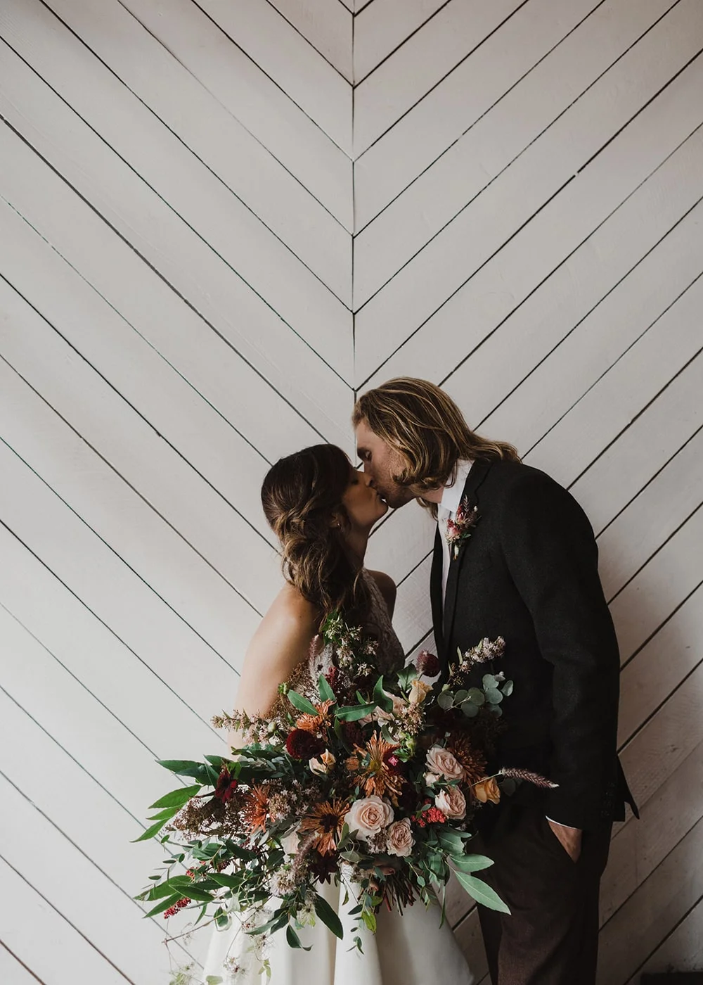 couple kissing in front of white wall with zig zag