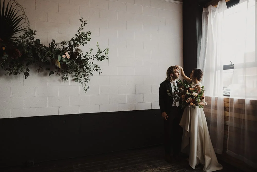 woman fixing man's hair in front of window before wedding ceremony at union pine