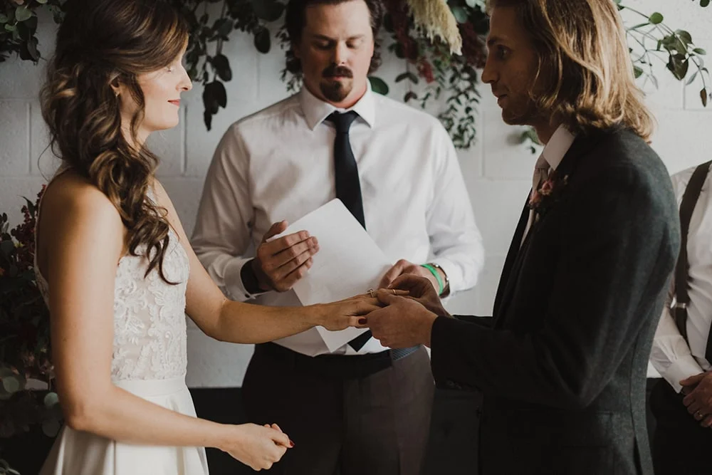 groom putting bride's ring on for the first time
