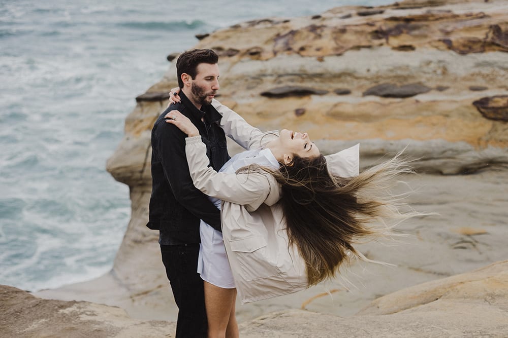 Groom dipping bride in front of rocks