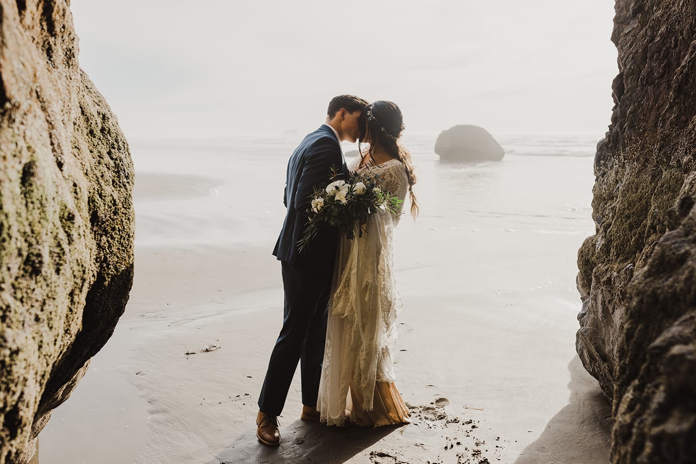 couple kissing in caves before elopement ceremony with ocean backdrop