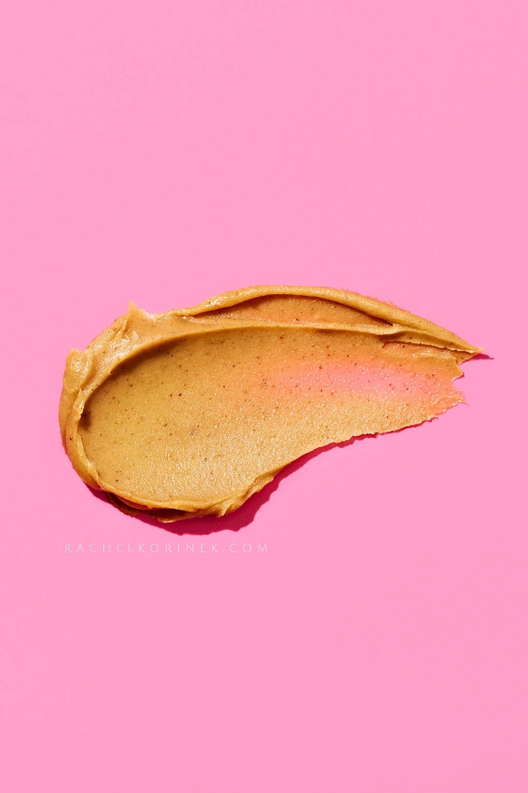  A smear of peanut butter on a bright pink surface. 