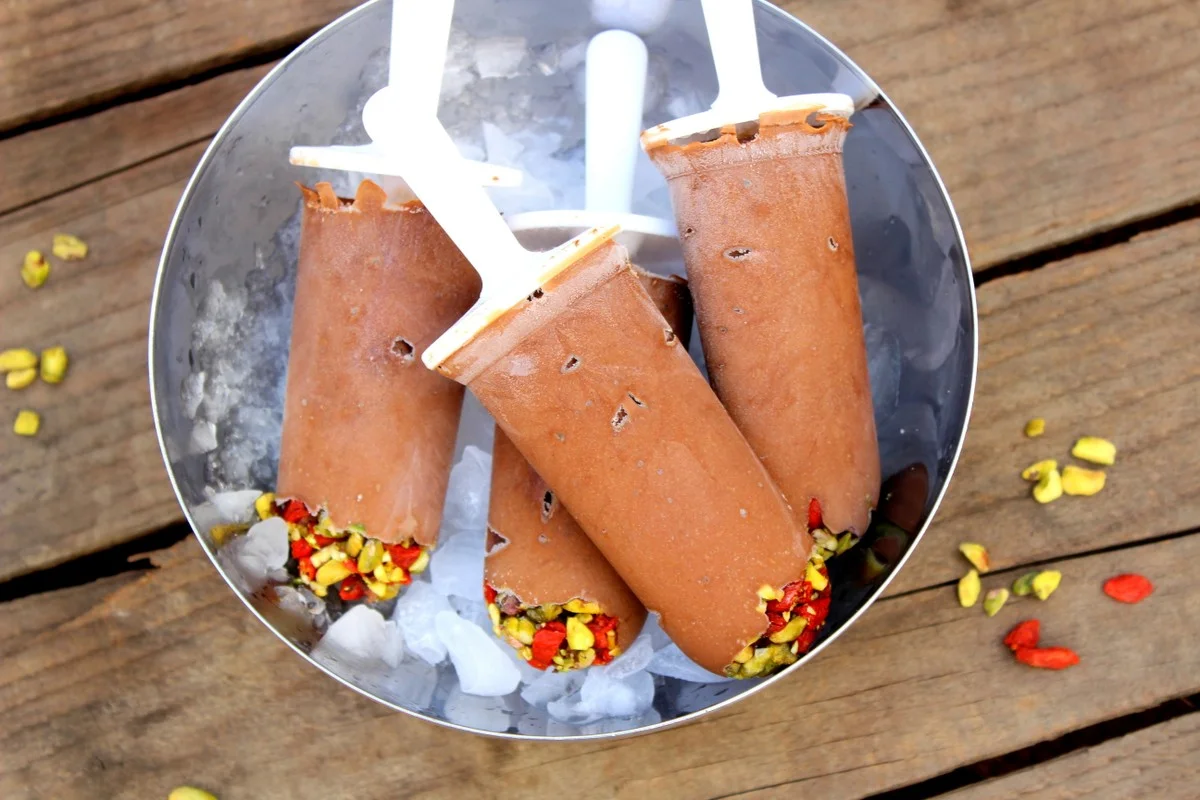 Chocolate fudgsicles topped with goji berries and pistachios