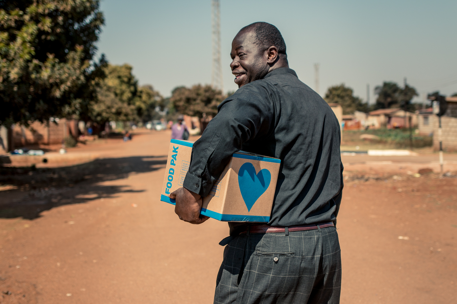  ZIMBABWE: [Home Visit] This is Bishop Musakwa. He's smiling as we walked to his home to share this food box with his family. Many times the pastors themselves are supported by the Food Pak ministry. We encourage the churches to prioritize meeting th