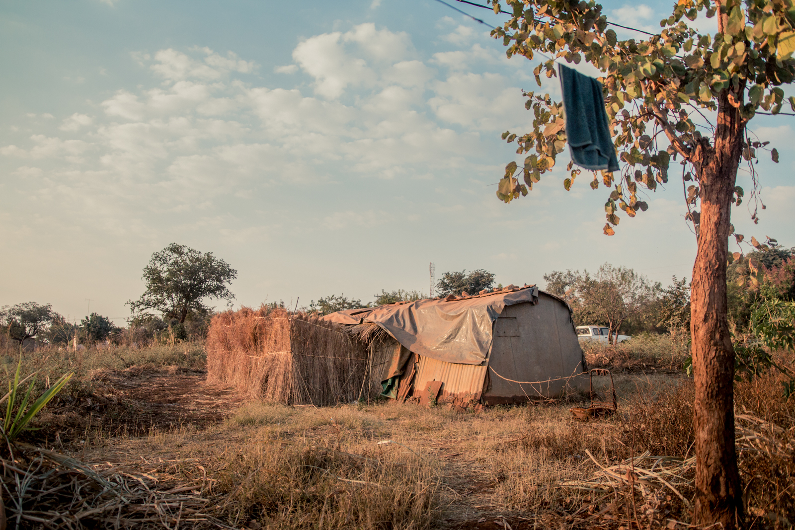  ZIMBABWE: [Home Visit] This is Patricia's home. A small hut made almost entirely of grass/straw thatching and plastic tarp. Patricia's a widow who lives a couple hours outside town on an abandoned farm land. The landowner recently gave her a pay or 