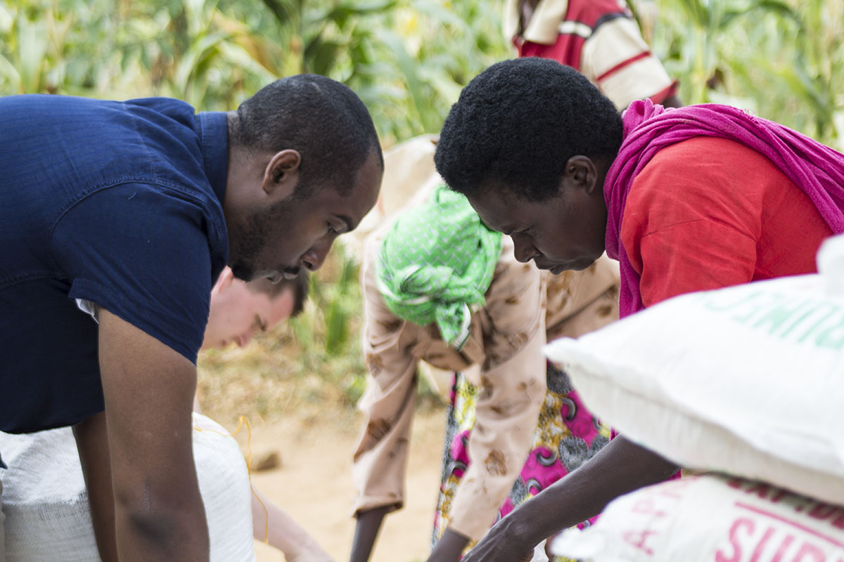  RWANDA: [Food Distribution] Some of the food recipients come to an evangelistic outreach at the church and after a short bible study receive bulk food. It was a joy to serve them, getting down on our hands and knees to fill their sacks with a months