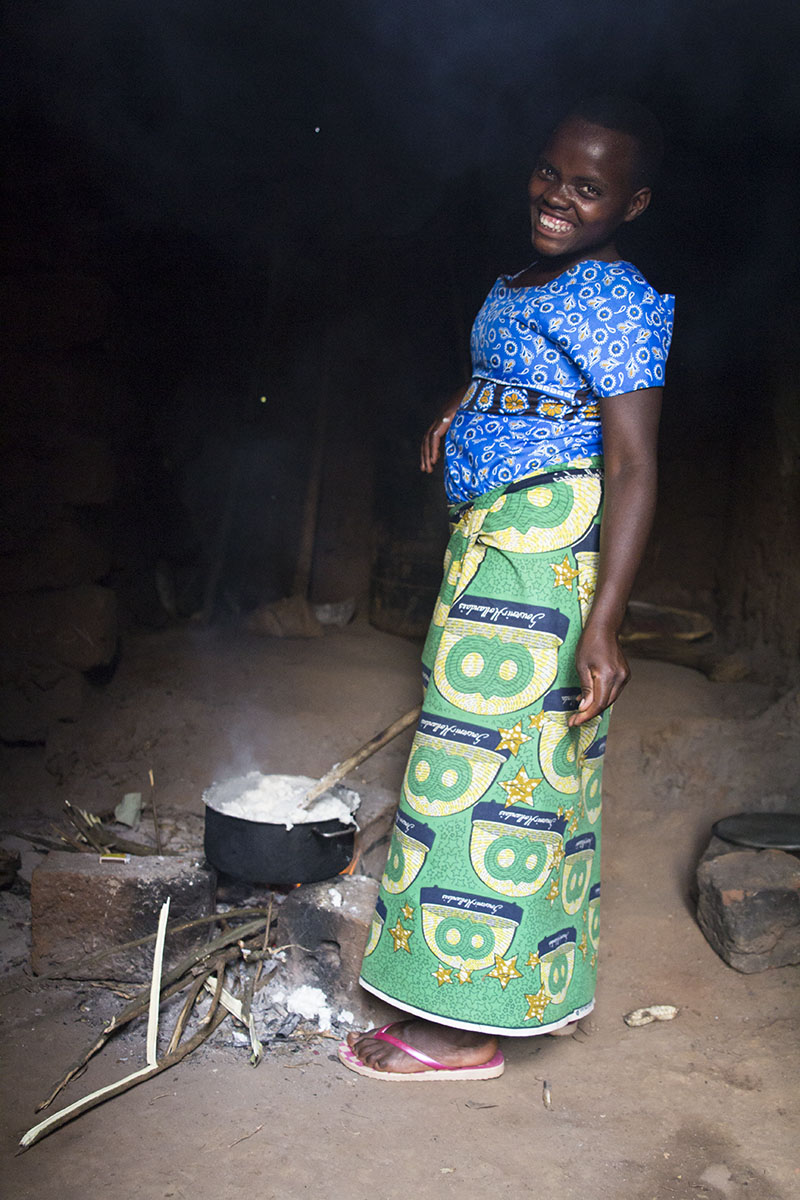  RWANDA: [Home Visit] Nakabonye's 12 year old daughter cooked a meal for the whole family. There was so much smoke from the burning straw inside the hut that we couldn't stand it. She just smiled and laughed at us. 