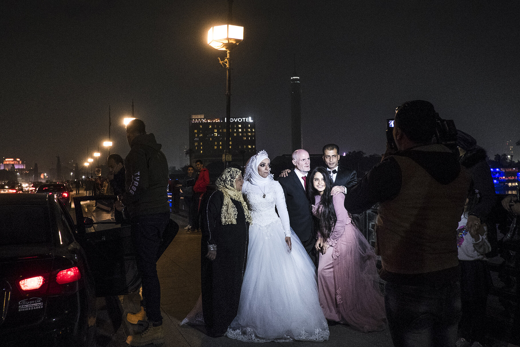 Together with her family, Gehad (25) poses for a traditional photo session on a bridge on Nile just after her wedding ceremony. In the life of Egyptian women, a wedding day is still considered a crucial moment of passage. Brides virginity, and in some social classes also circumcision, are necessary for finding a wealthy and appropriate husband. Large number of marriages are still arranged by the families and a future husband, often much older than his wife, is demanded to pay a price for a bride to her family and provide a place where they are going to live together after the ceremony.Women are expected to get pregnant as soon as even 2 months after the ceremony. Lack of pregnancy can lead to a divorce or give the husband permission to remarry. January 2019, Cairo, Egypt