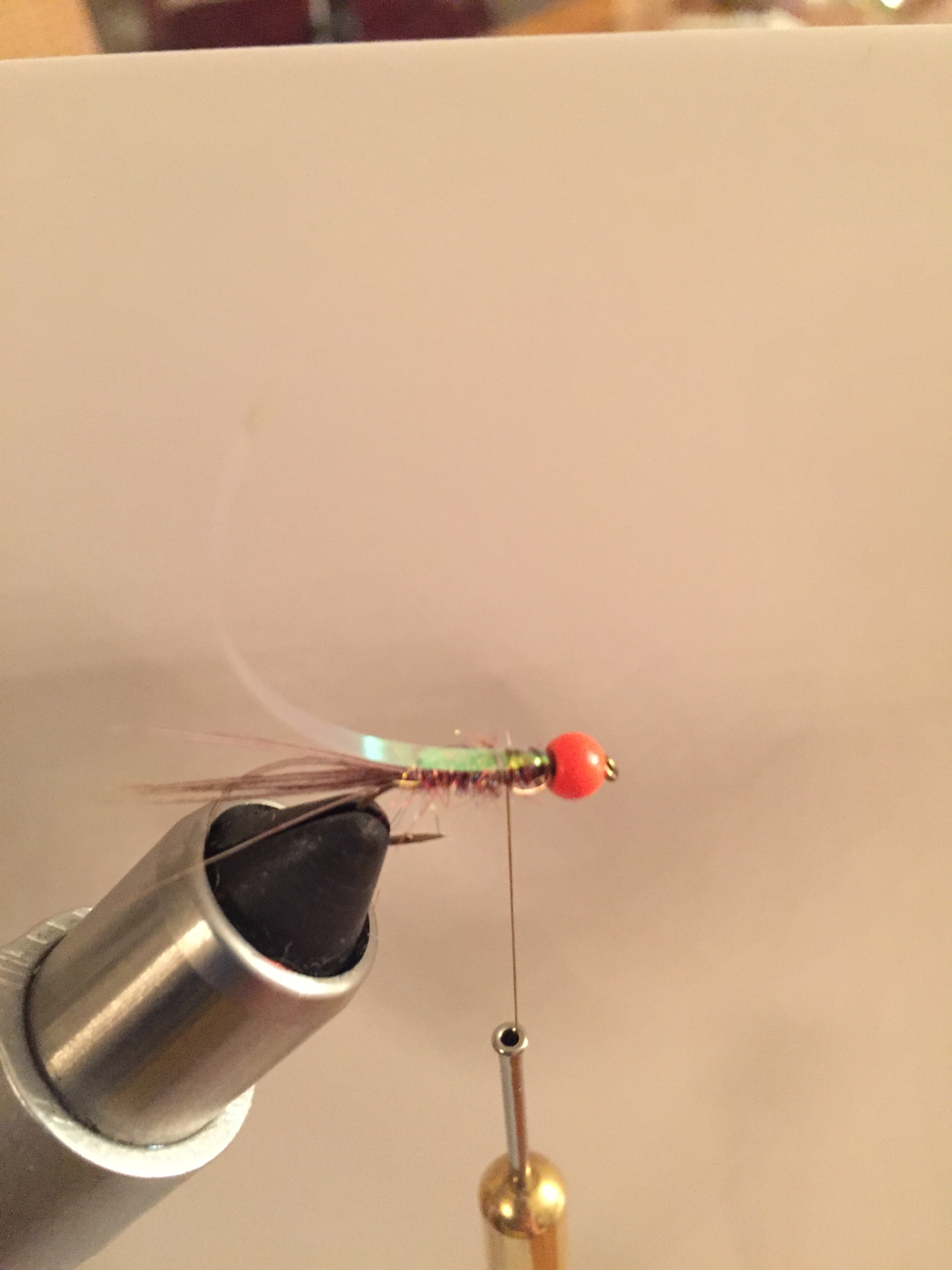 Step 5: Tie in a 1" section of mirage of Mirage Pearl UTC tinsel directly behind the bead. Wrap down approximately one quarter of the hook shank with pearl tinsel.