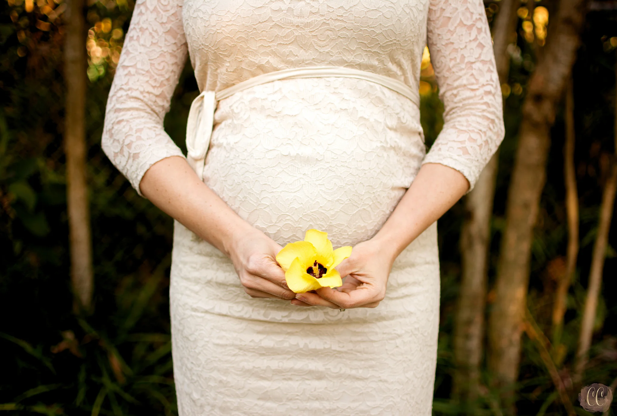 Pregnant woman poses with yellow flower over belly for Tampa maternity photographer Carlie chew Photography 