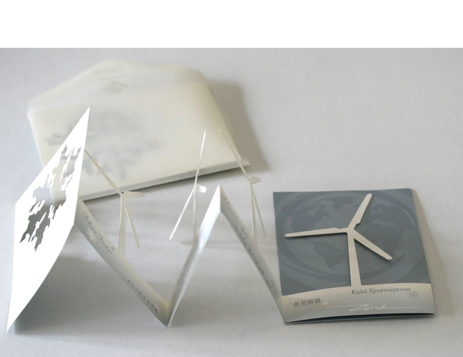  The card is removed from the translucent envelope and begins to unfold, unveiling the wind turbine shapes 