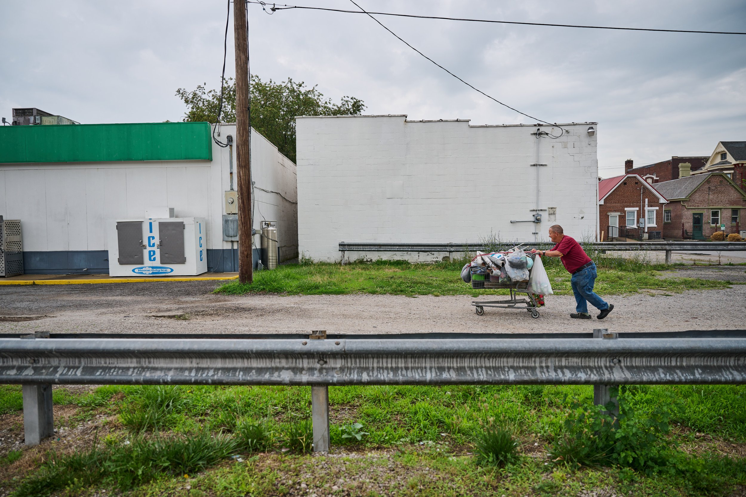  7/8/23—Cynthiana, Kentucky — Fryman walks with his shopping cart back to the gas station as storms begin to hit Cynthiana. When the weather turns bad, he often hangs out inside the store, where he jokes with customers and catches his breath until th