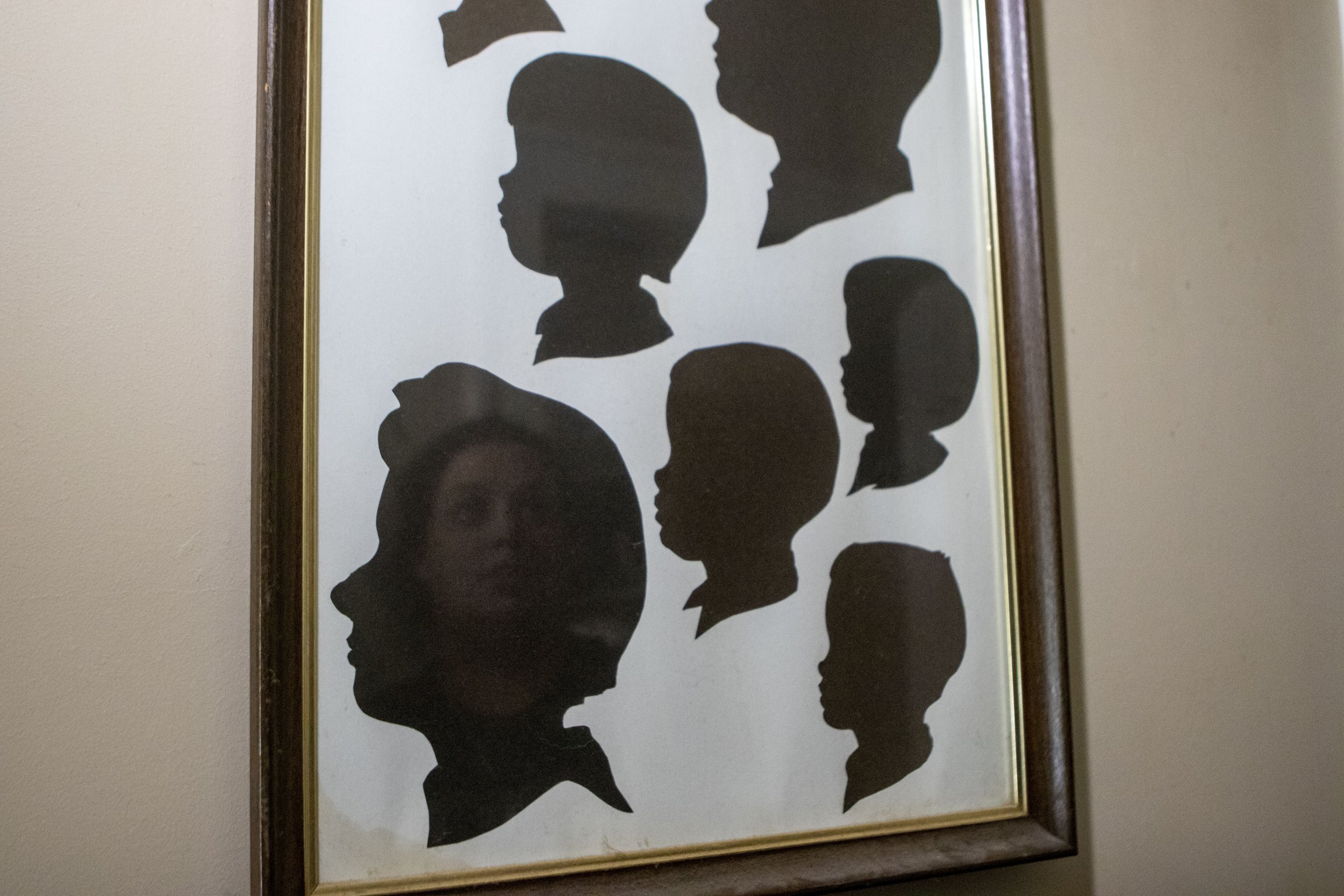  Breanna looks up a shadow portrait of her mother and other family members. The house is full of reminders and photos of Kay’s legacy. 