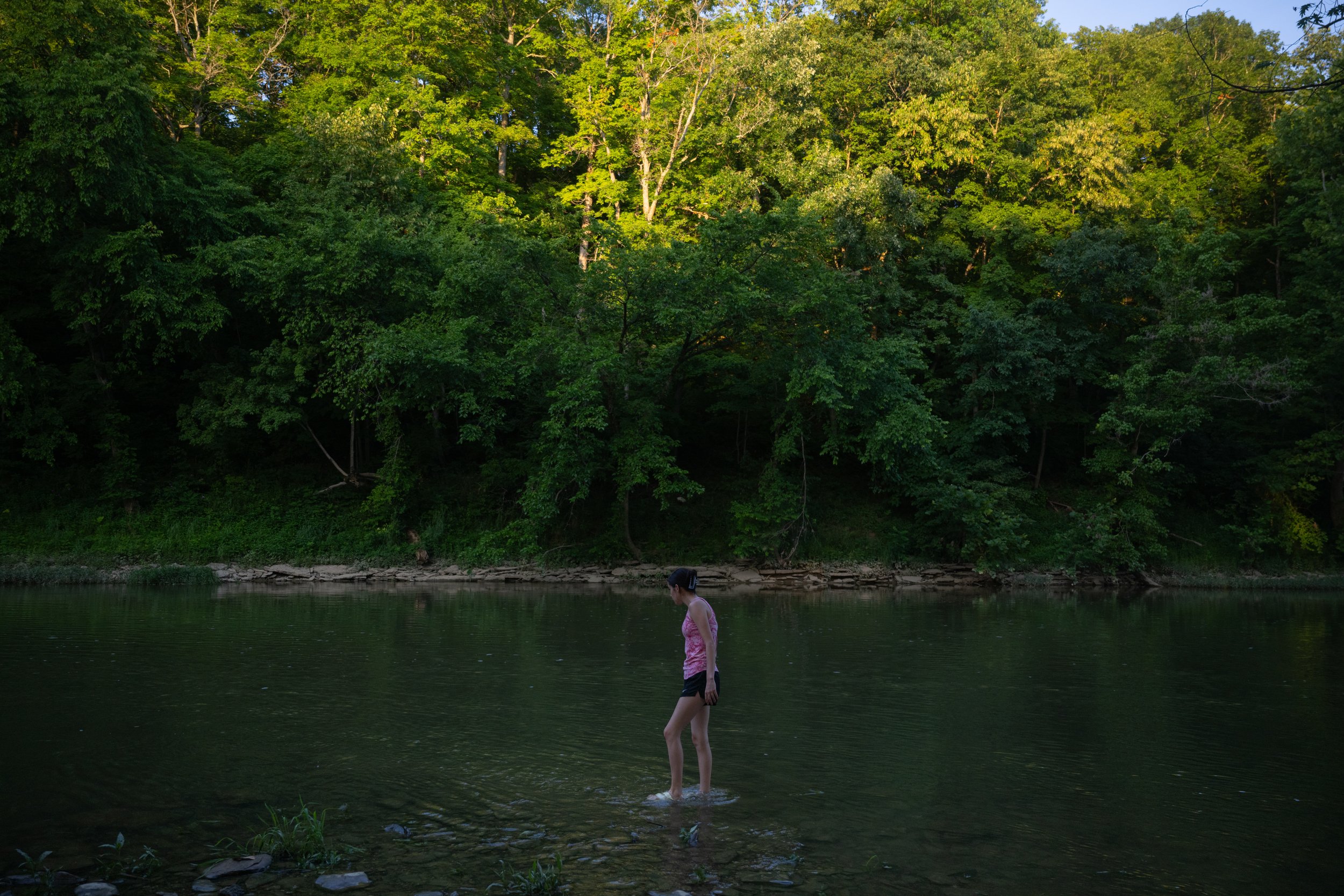  7/7/23 -- Cynthiana, Kentucky —  Ashlynn McNees, 18, looks for rocks to skip with while walking in the South Fork Licking River in Cynthiana, KY on July 7, 2023. 